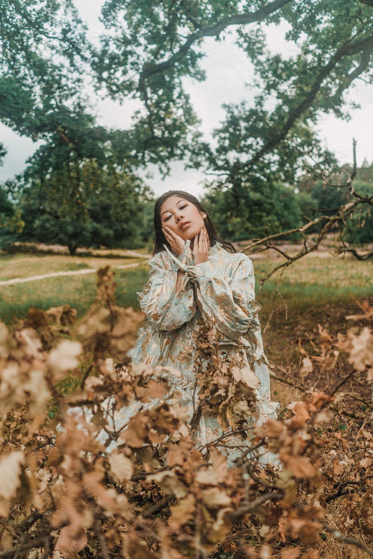 a woman kneels in a pile of fallen leaves