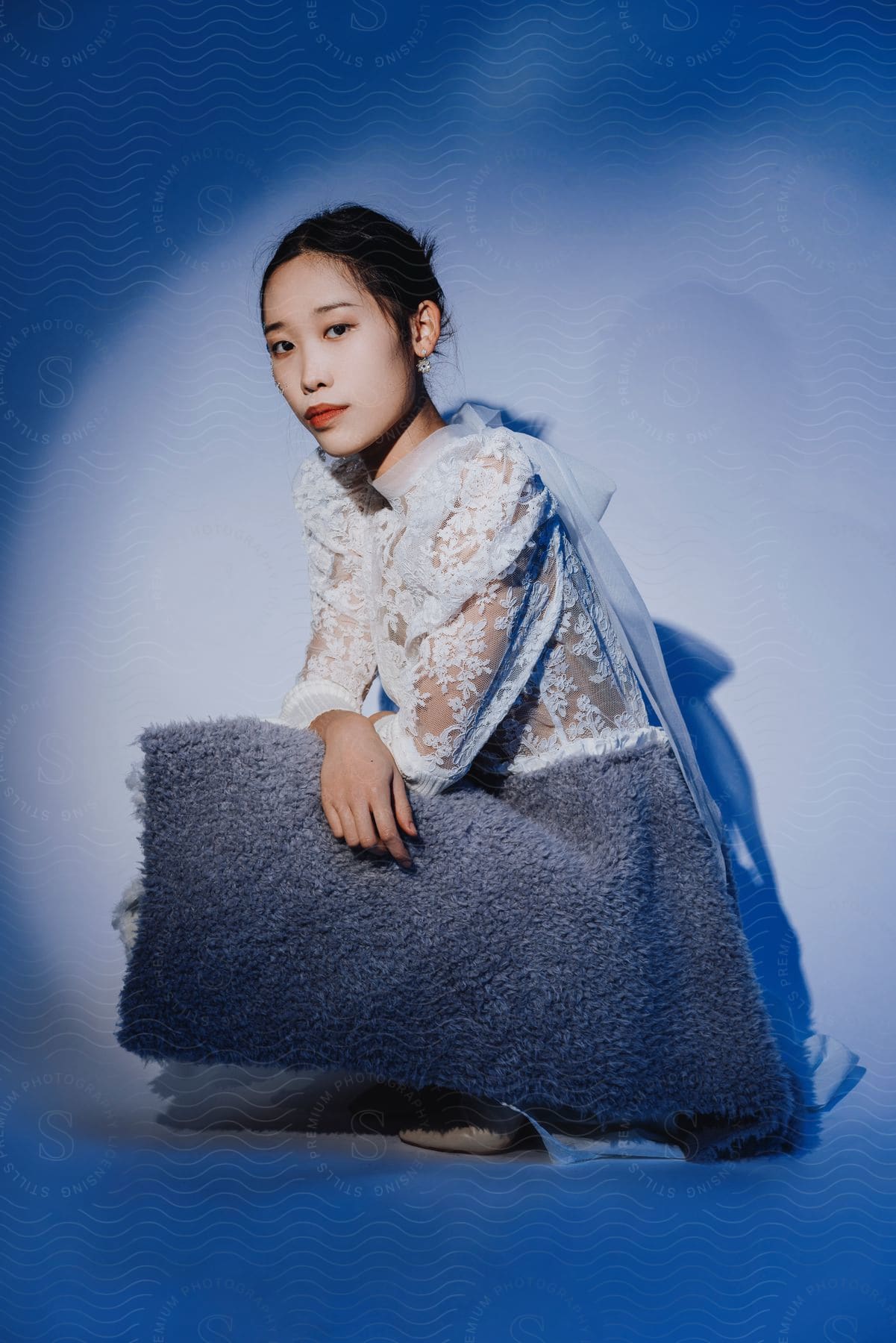 A woman modeling some clothes in a studio with a blue backdrop.