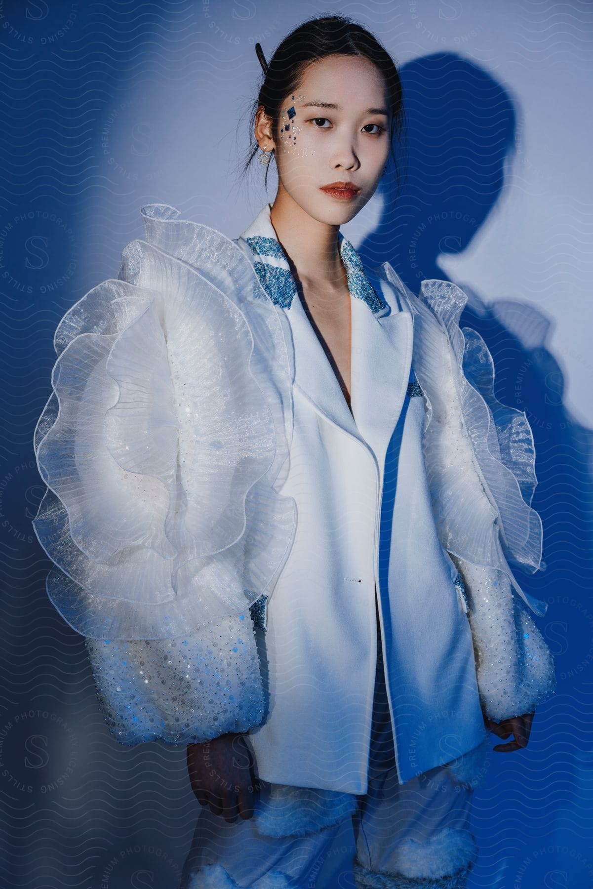 a model wears a blazer with decorative tulle and sequin sleeves