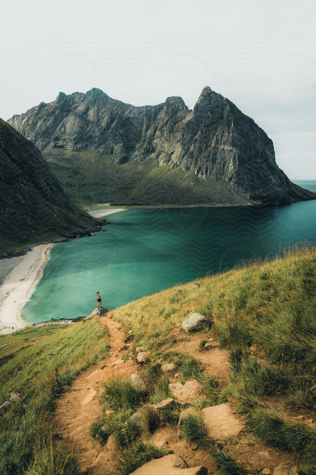 a woman takes in the view along the coast below a mountain range