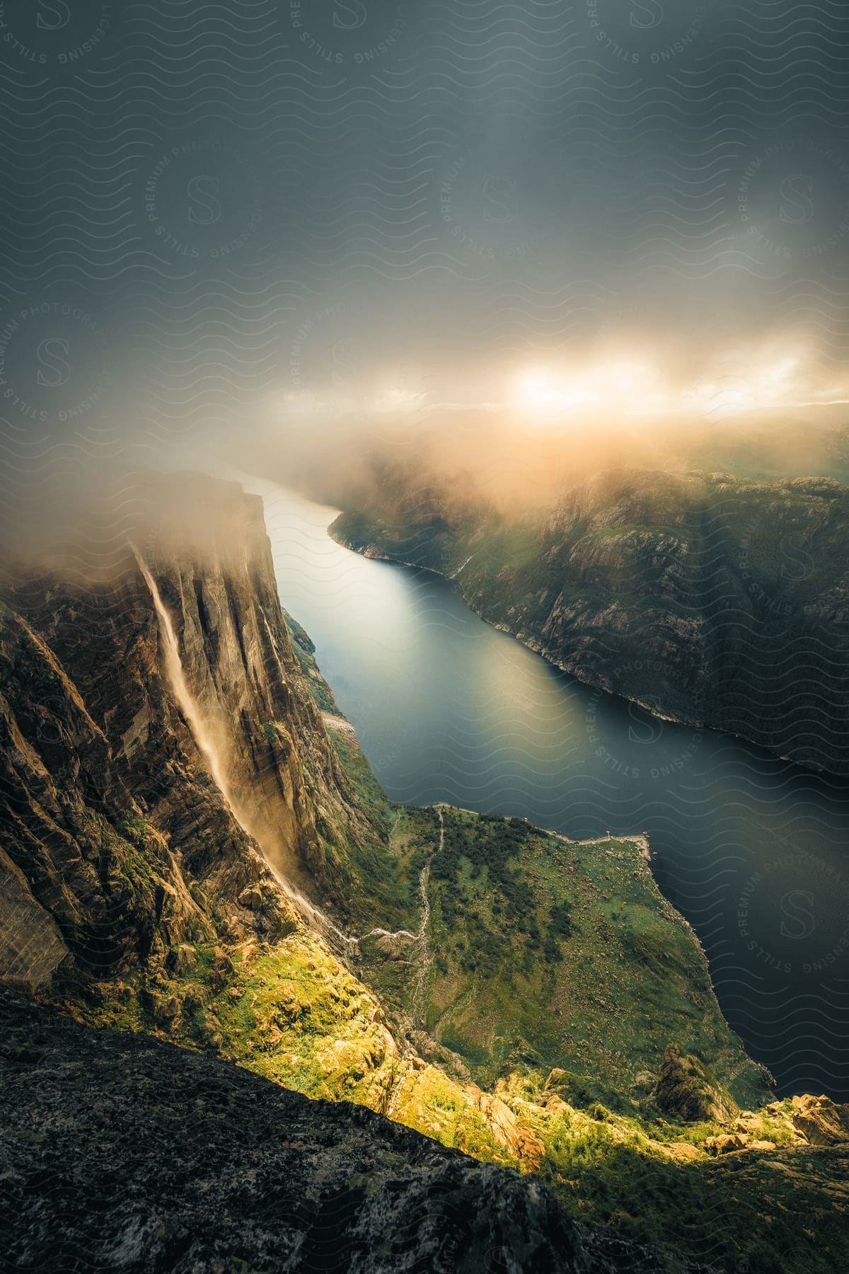 Stock photo of a river running at the base of some mountains with clouds in the distance.