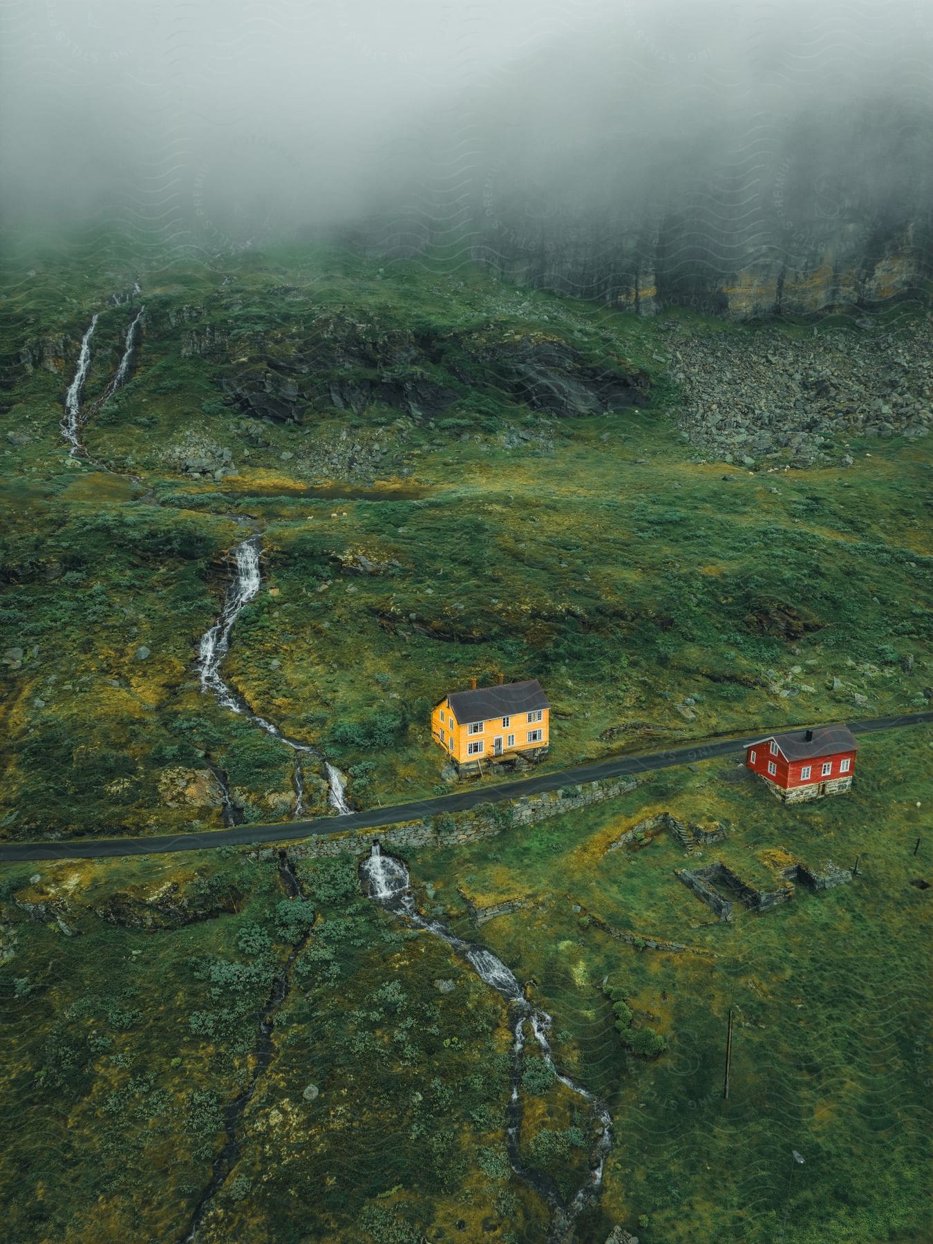 Two houses are on a rural road with a frozen stream over the hills