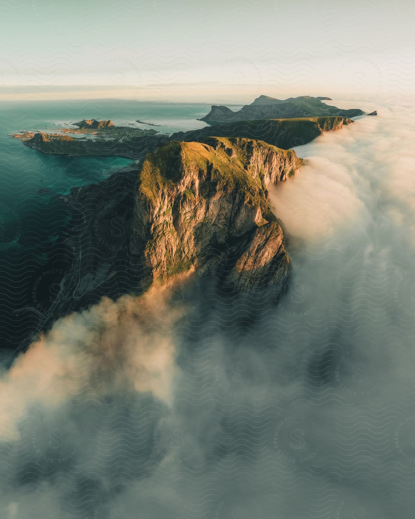 Clouds cover a mountain cliff overlooking a coastal landform