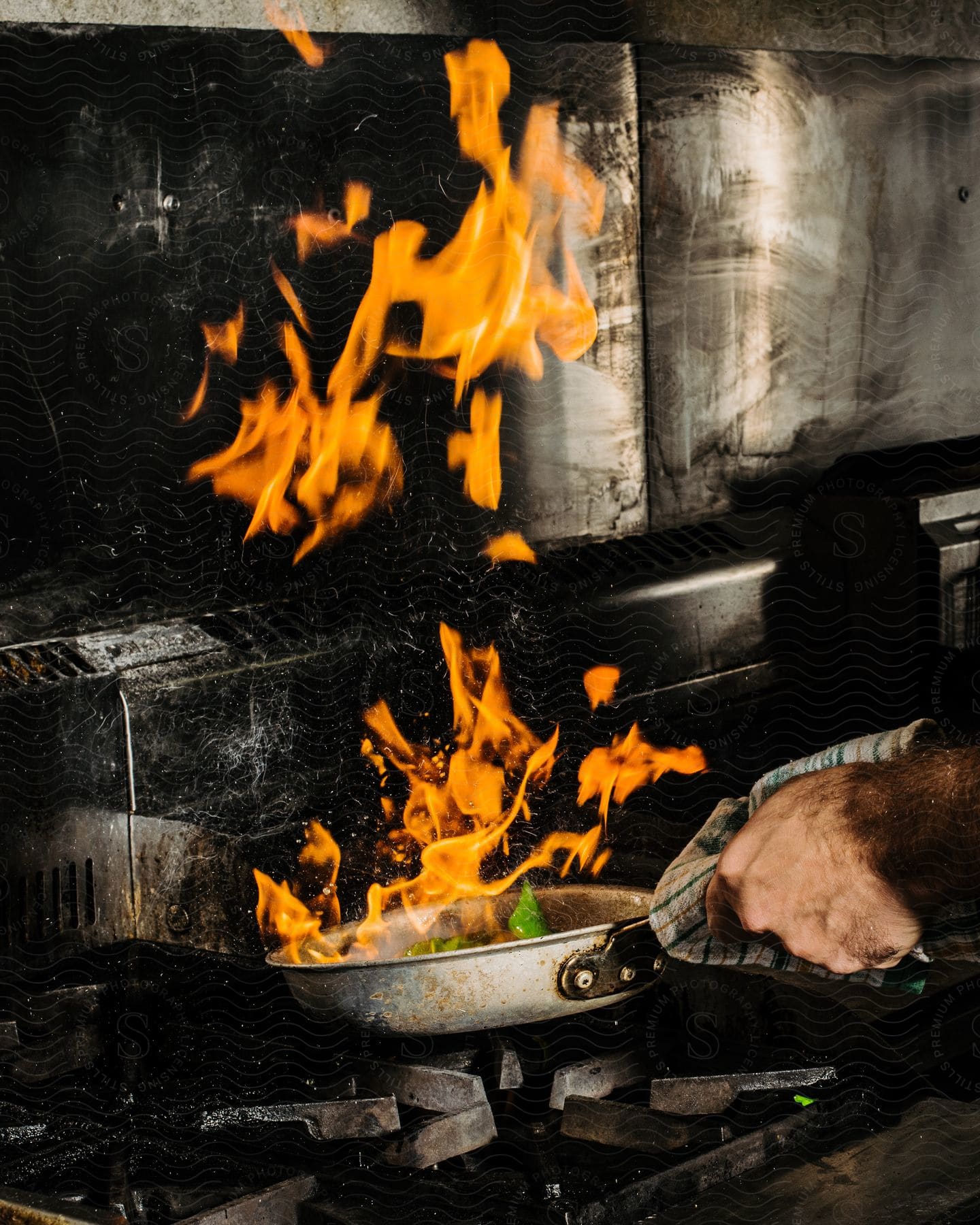 Someone is cooking on a stove and there is a fire.