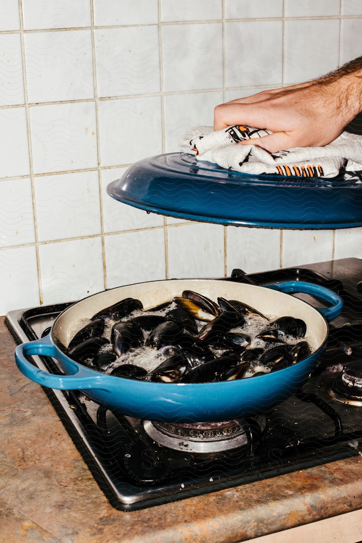 a man opens a lid to check on mussels cooked in a dutch oven