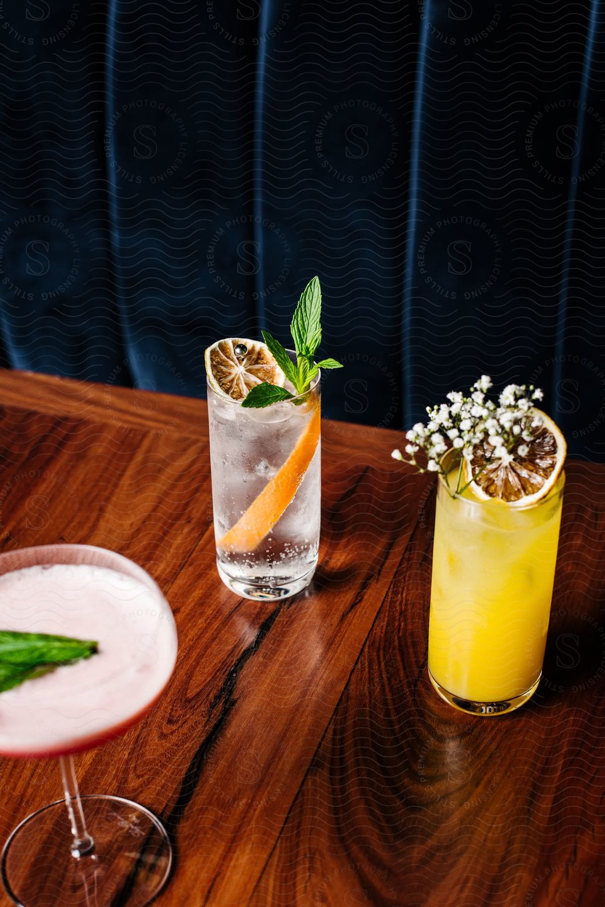 Trio of mixed beverages sit on wooden table.