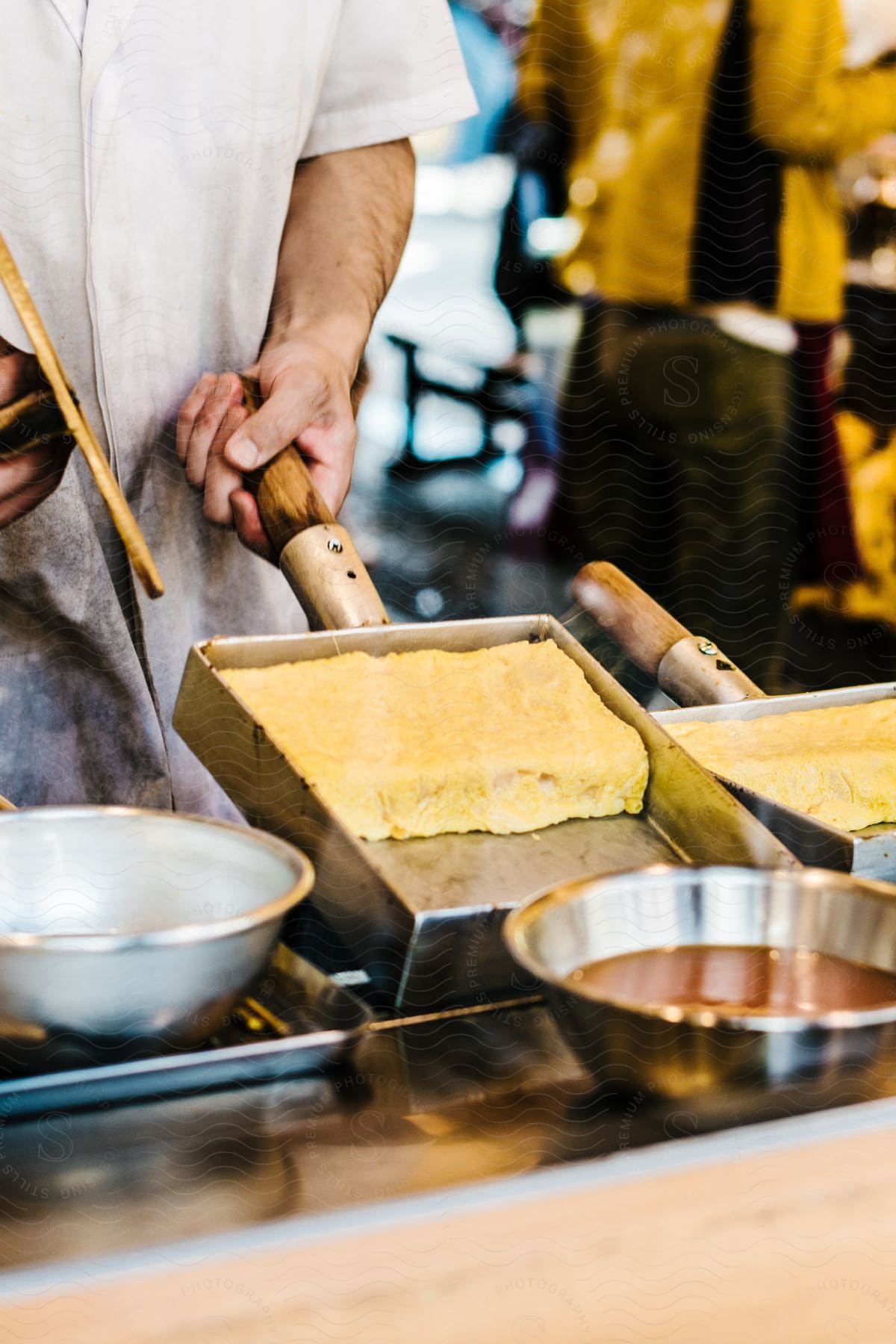 A chef standing in a kitchen holds a baking pan with half of a souffle still in it.