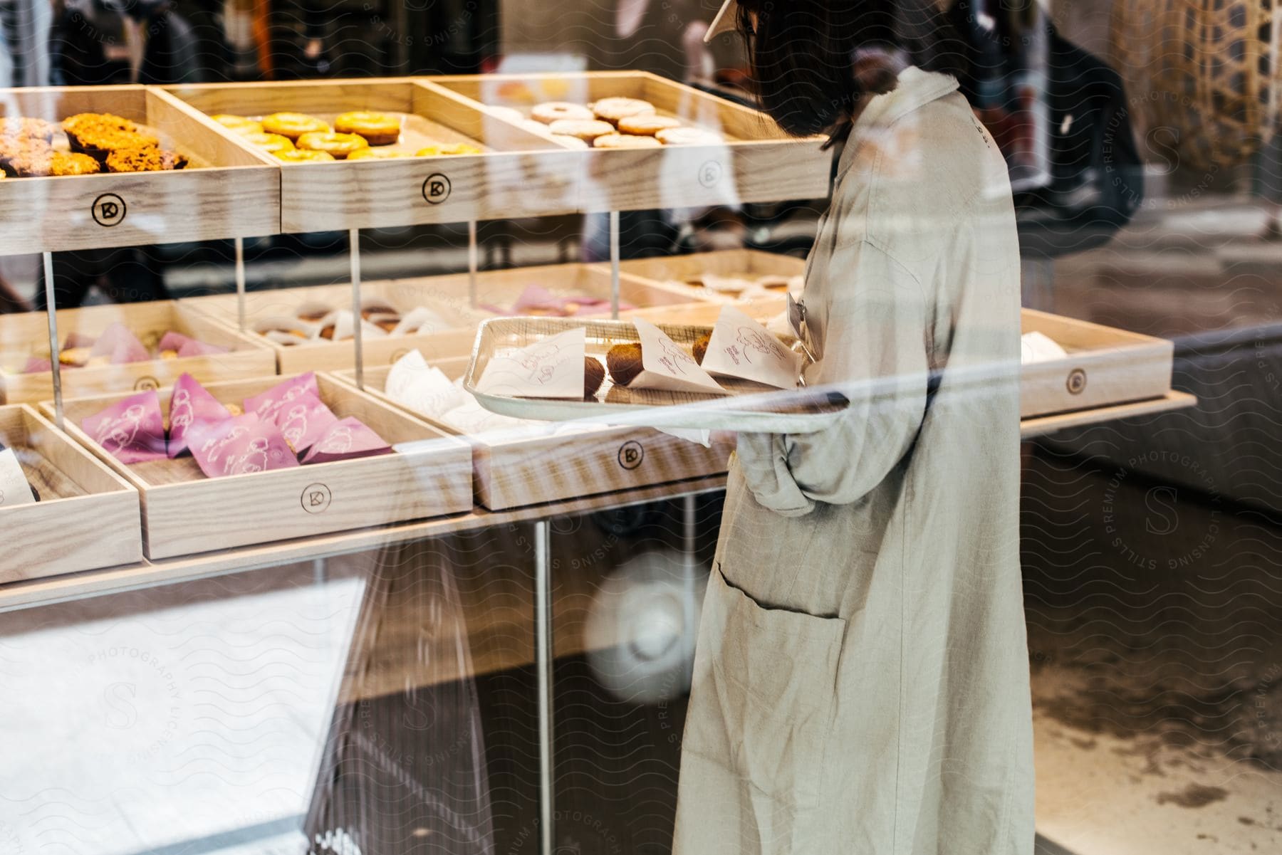 A customer in a trench coat picks out baked goods in a bakery.