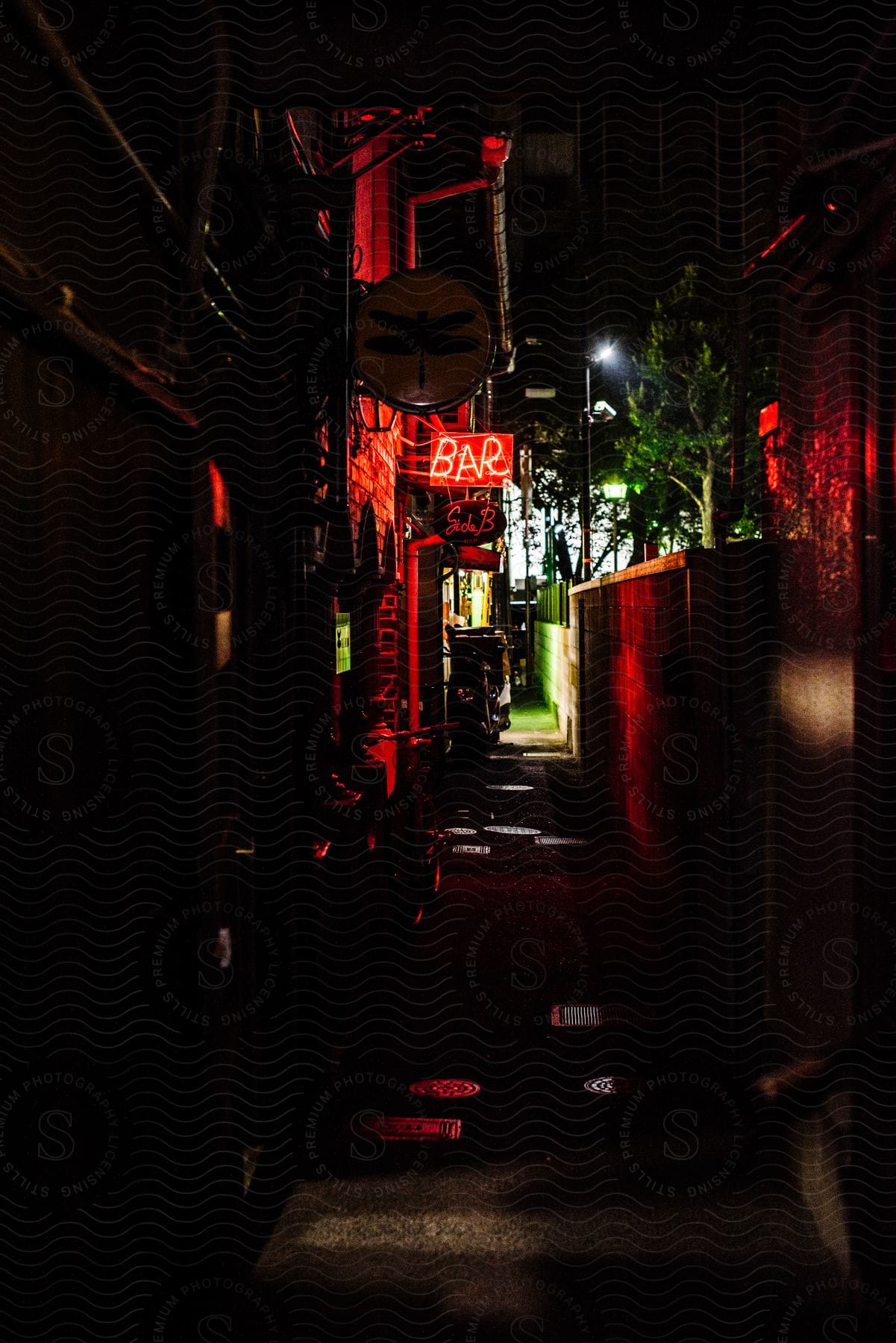 A narrow street with open bars at night in the city.