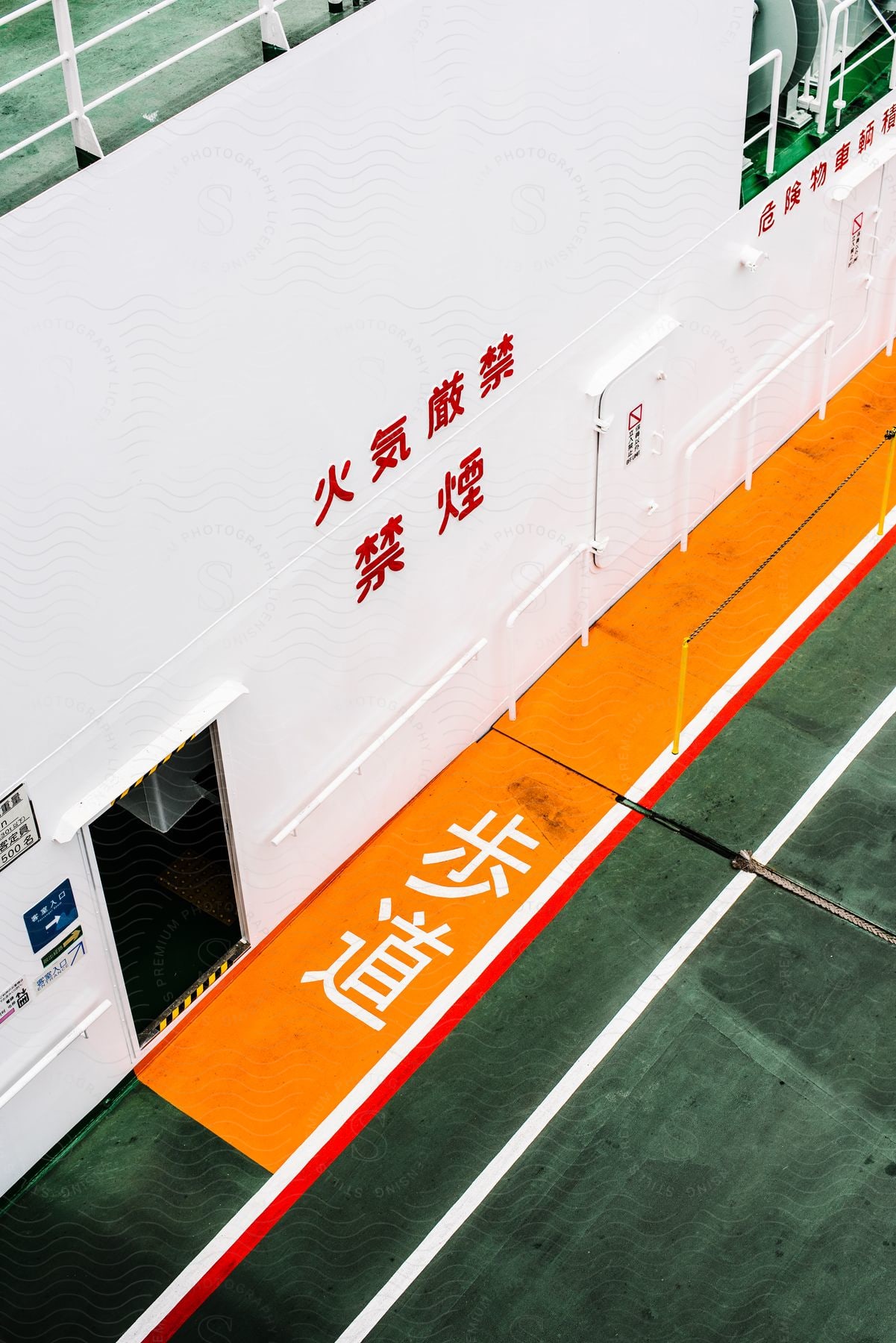 Stripes and Asian writing on a playing field and wall with a door with a railing above