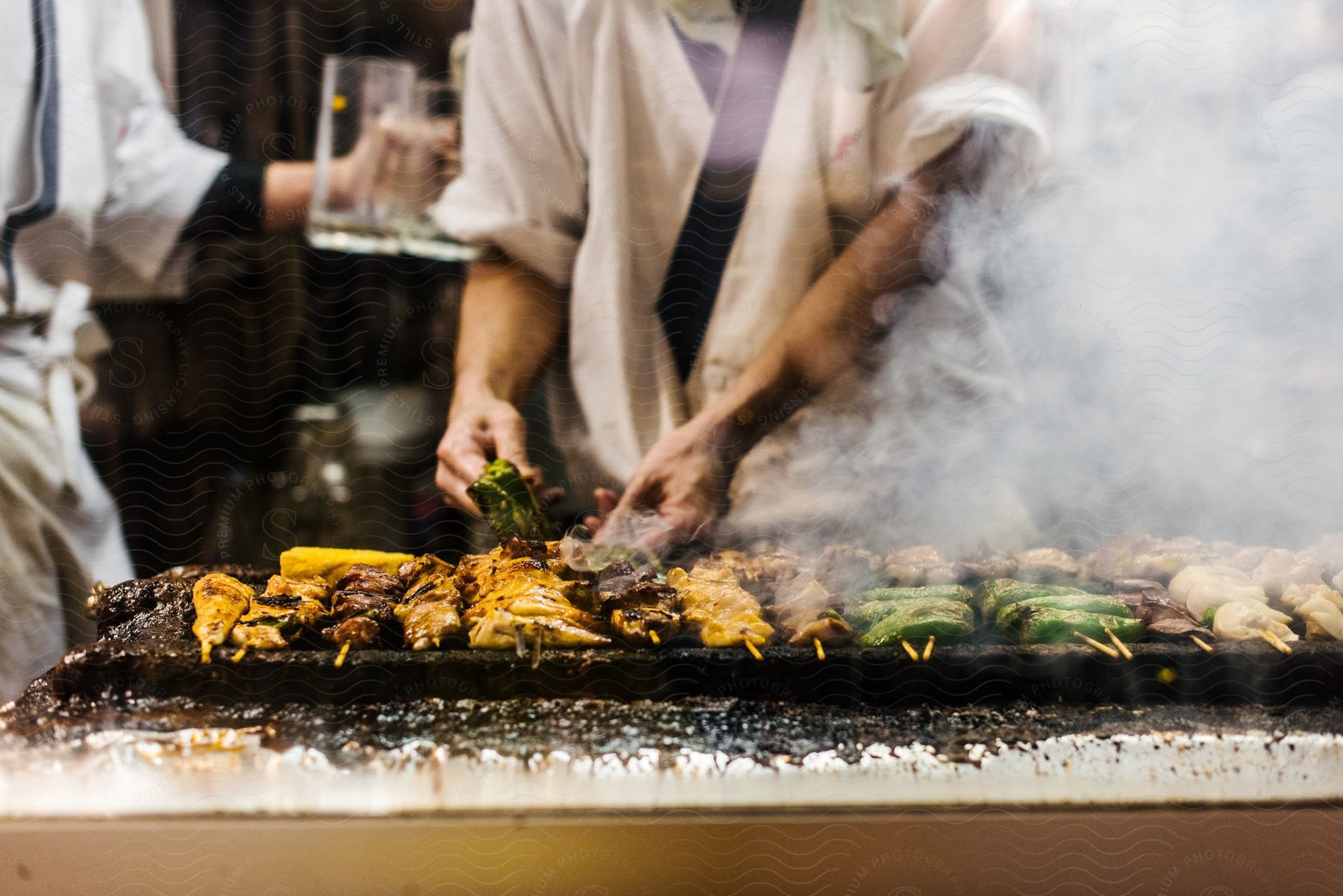 A person prepares a large number of kebabs on skewers in order to cook them on a grill.