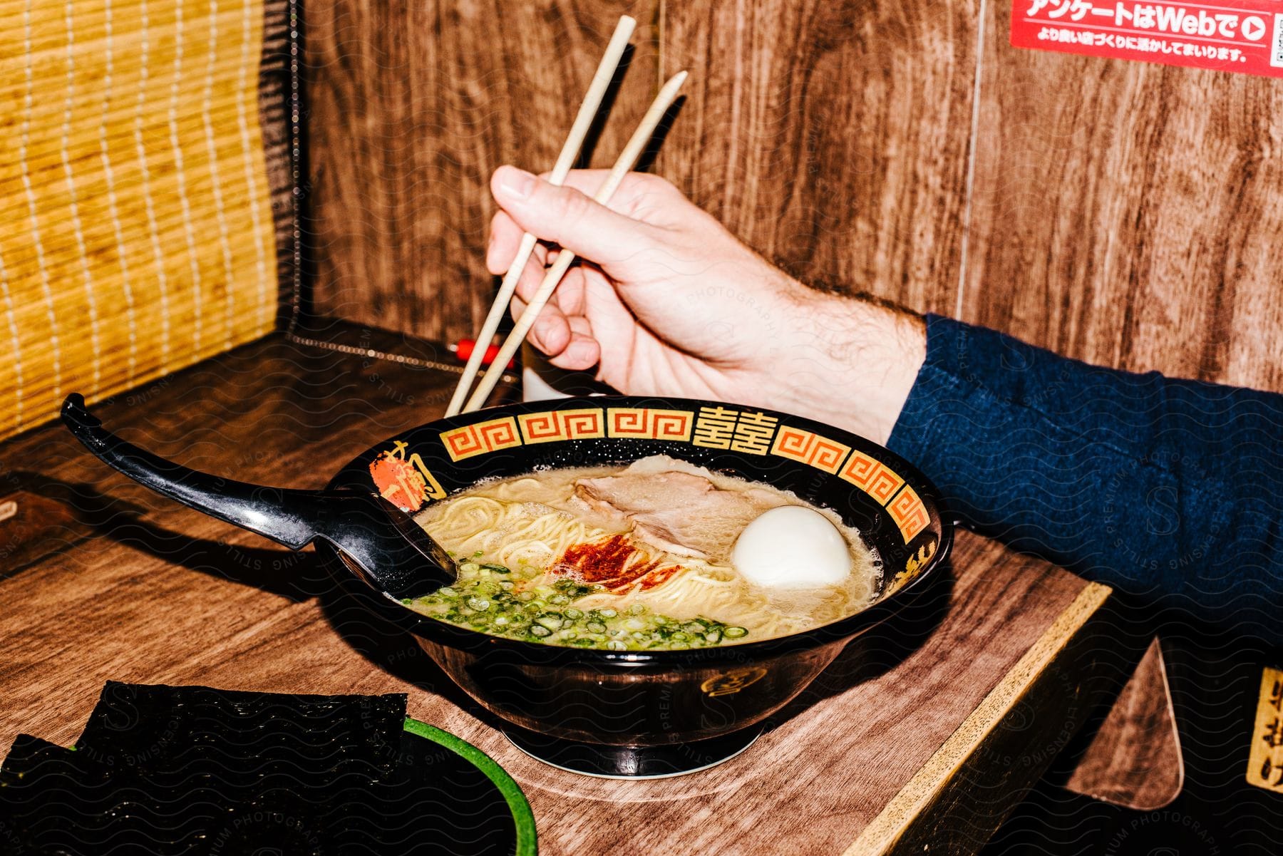 A person's right hand is holding chopsticks as they eat from a large bowl