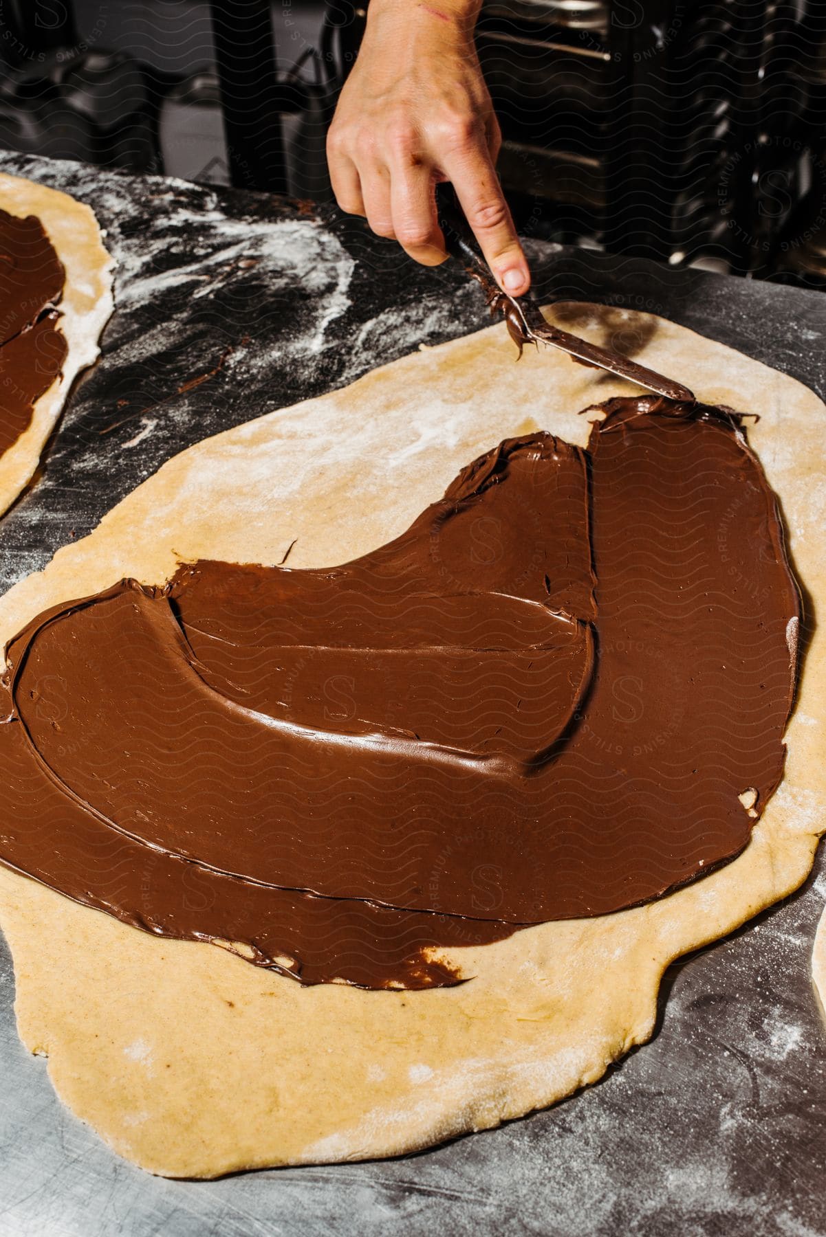 Creamy chocolate sauce being poured onto pasta in preparation.