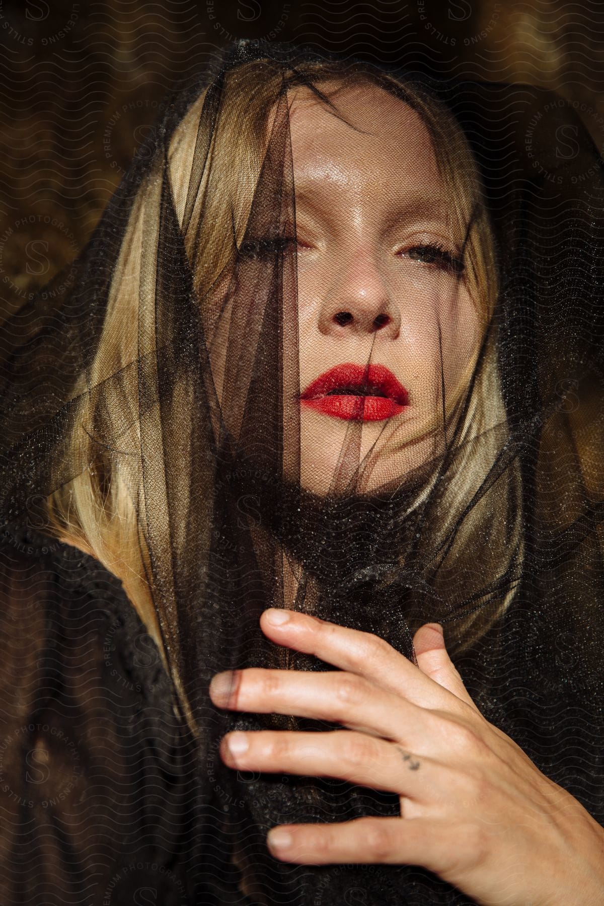 Woman with blonde hair wearing a black veil and red lipstick