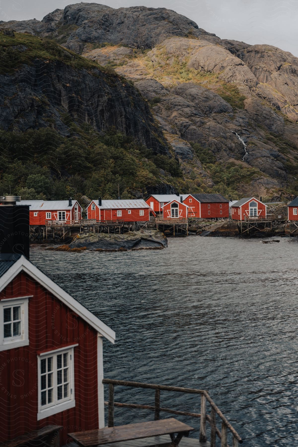 a small town close to shore with houses painted red next to a rock mountain