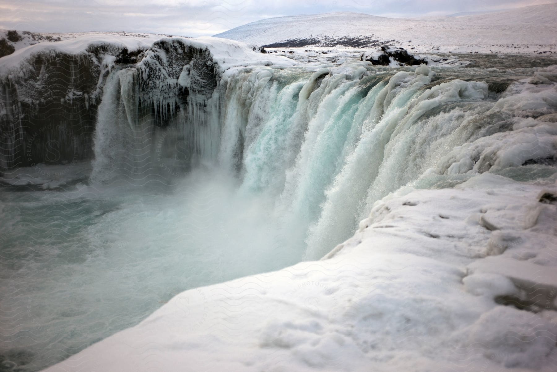 Aerial of a waterfall with ice in the mountainous landscape.