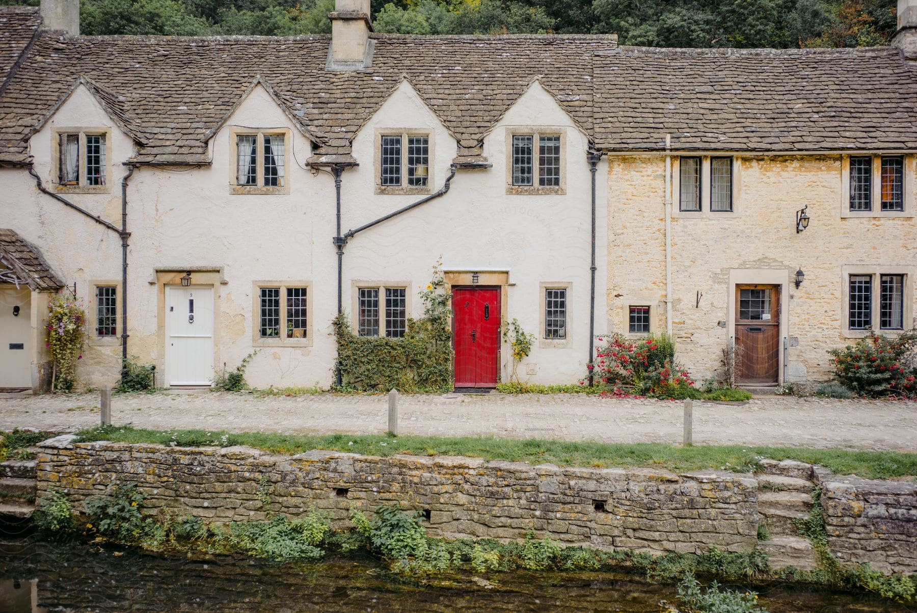 Steps in a stone wall lead to a road in front of row houses with different color doors