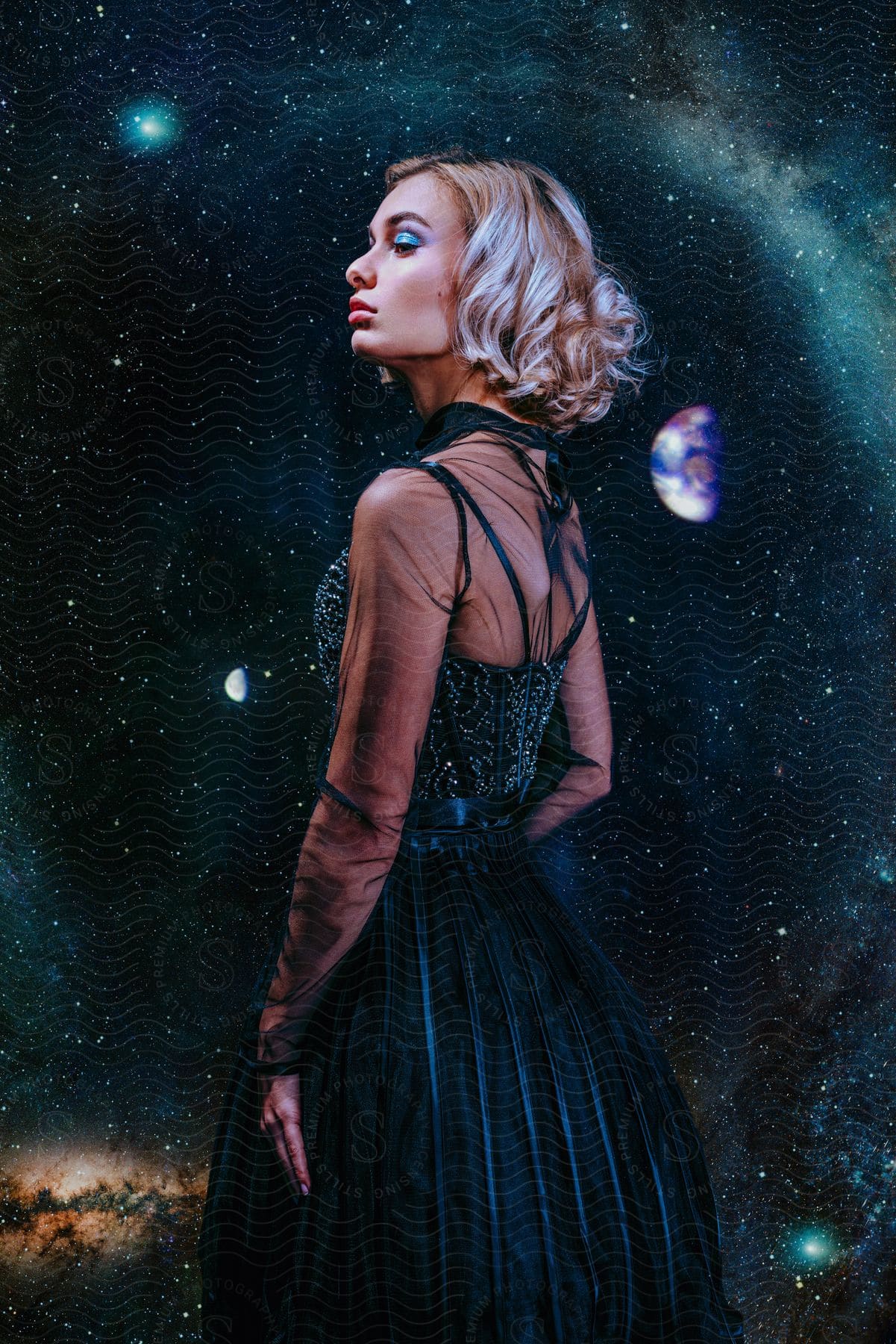 Stock photo of a woman models a sparkly and sheer black dress with a milky way night sky behind her