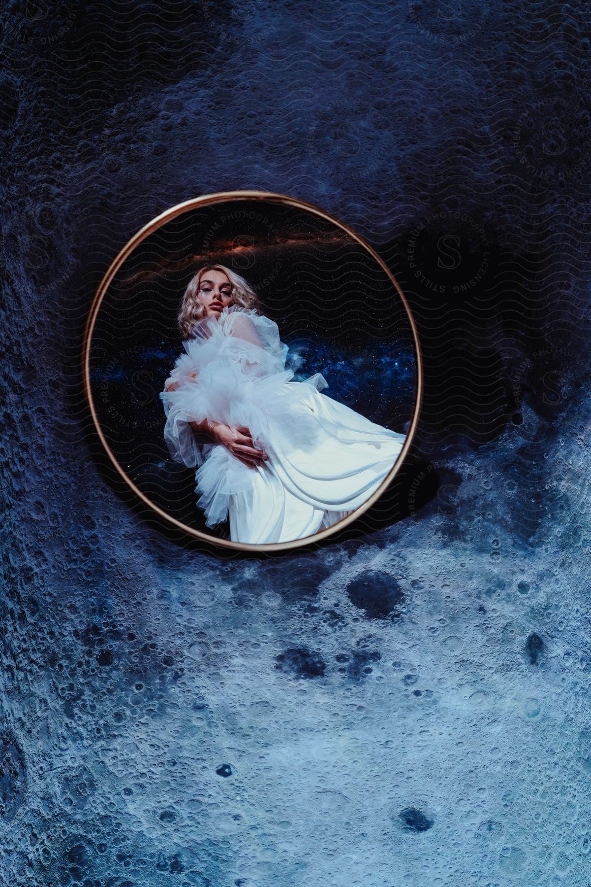 Mirror lying on uneven stone reflects woman wearing white dress and surrounded by outer space.