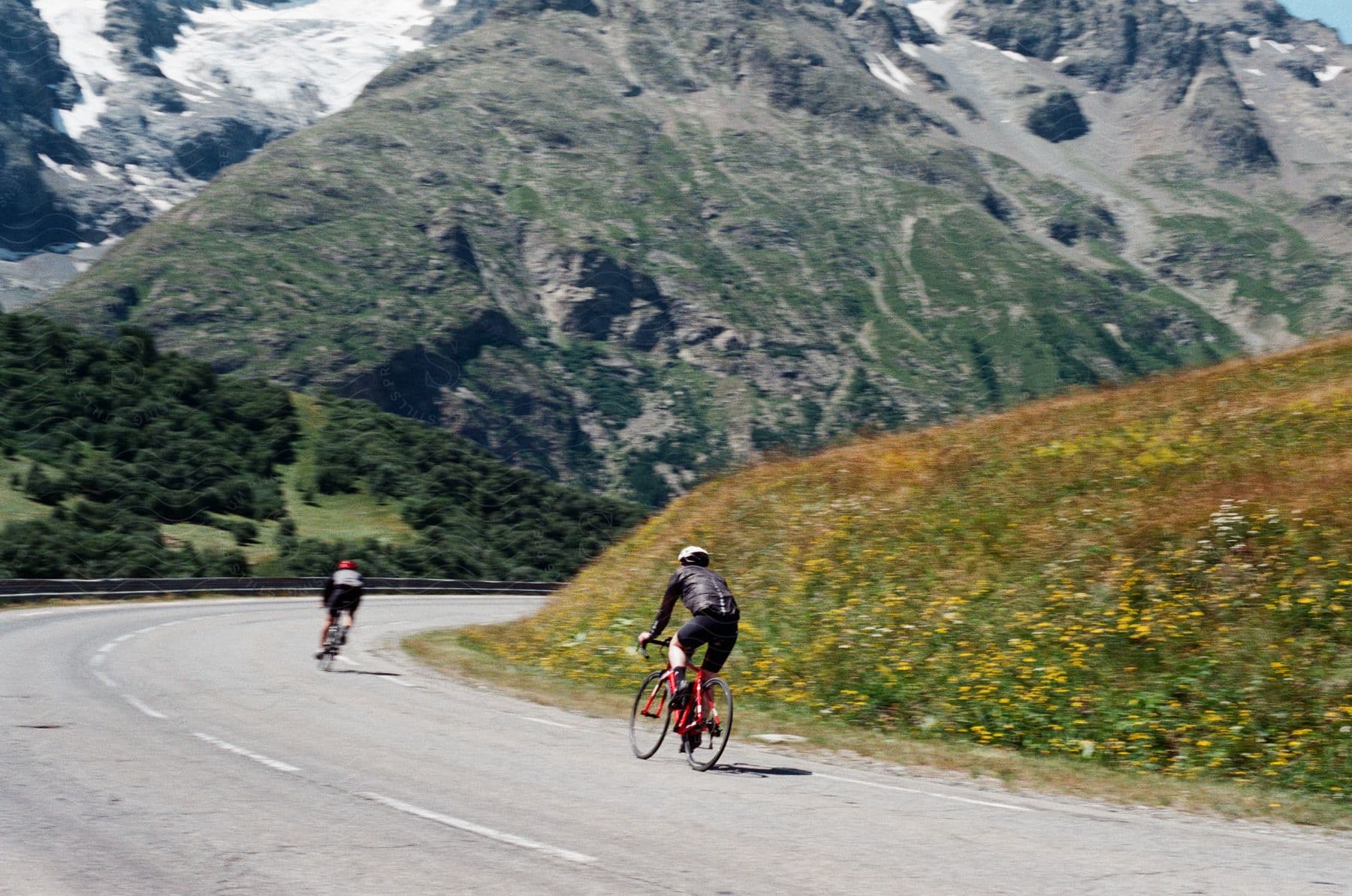 Two cyclists riding downhill on a mountain highway.