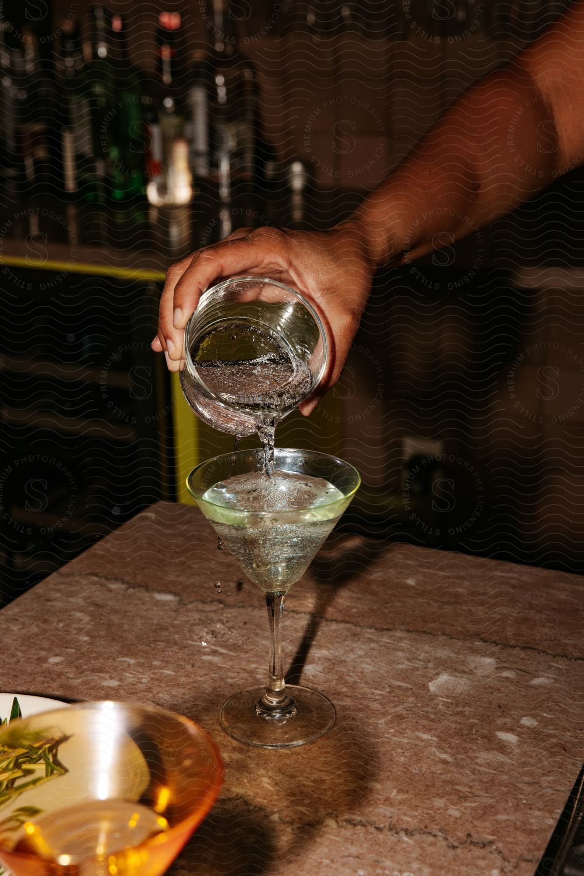 A person pouring a drink into a martini glass