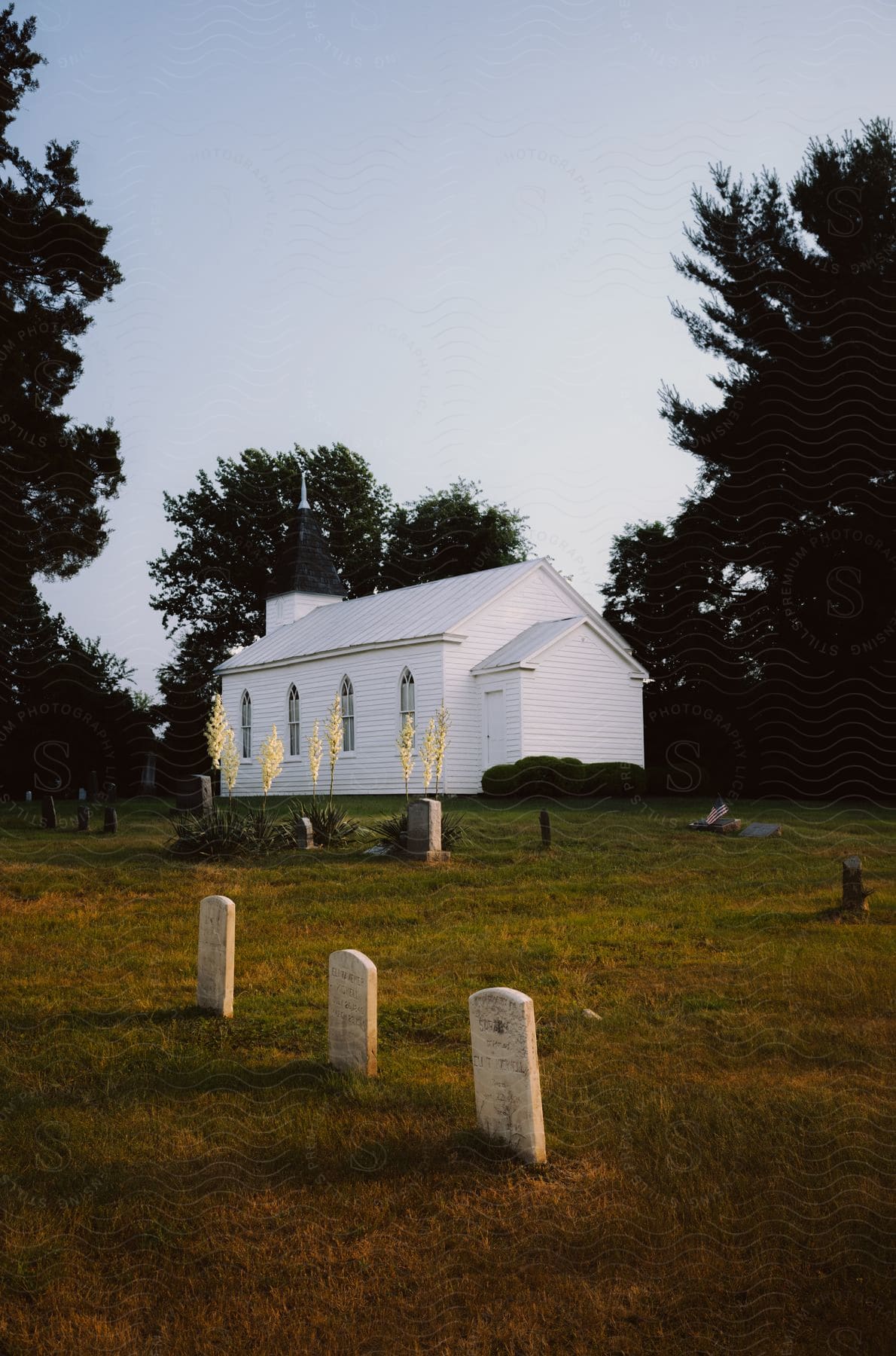 Gravestones stand in a lot next to a small church