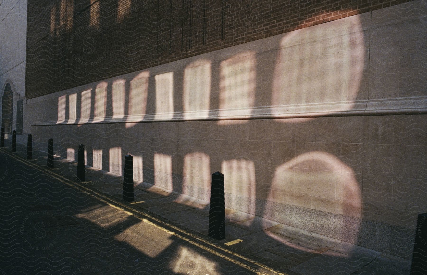 Sun casts arches onto building near street.