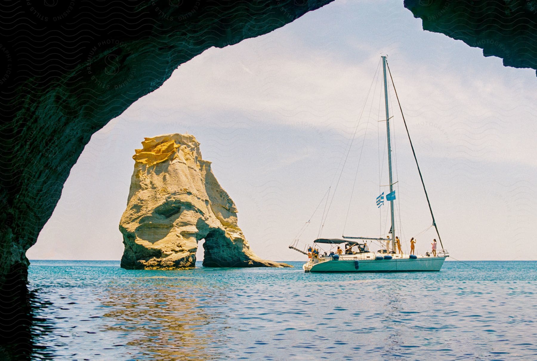 View through an arch of a boat filled with people sailing near an arch rock formation