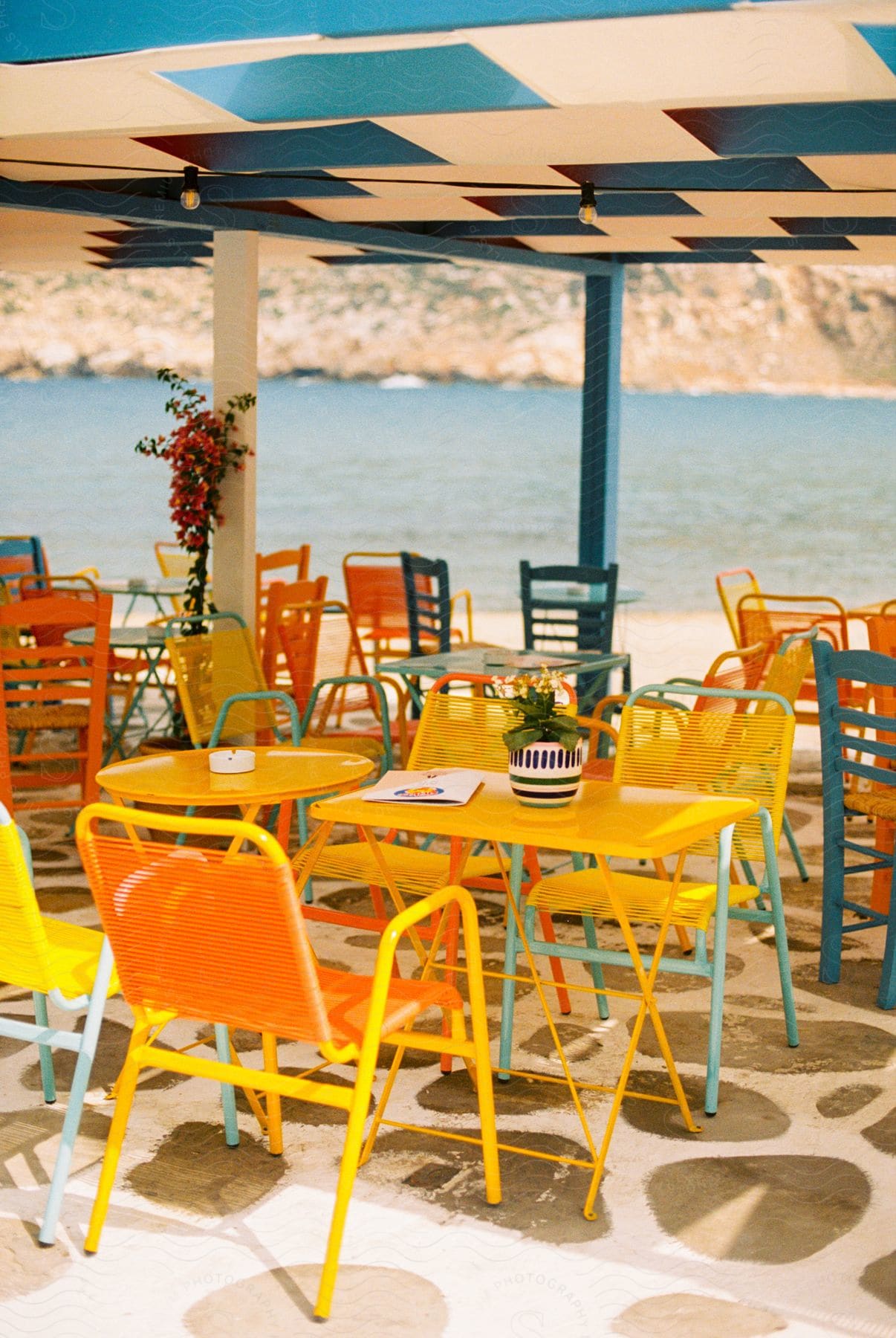 A yellow table and chairs on a restaurant patio on the shore.