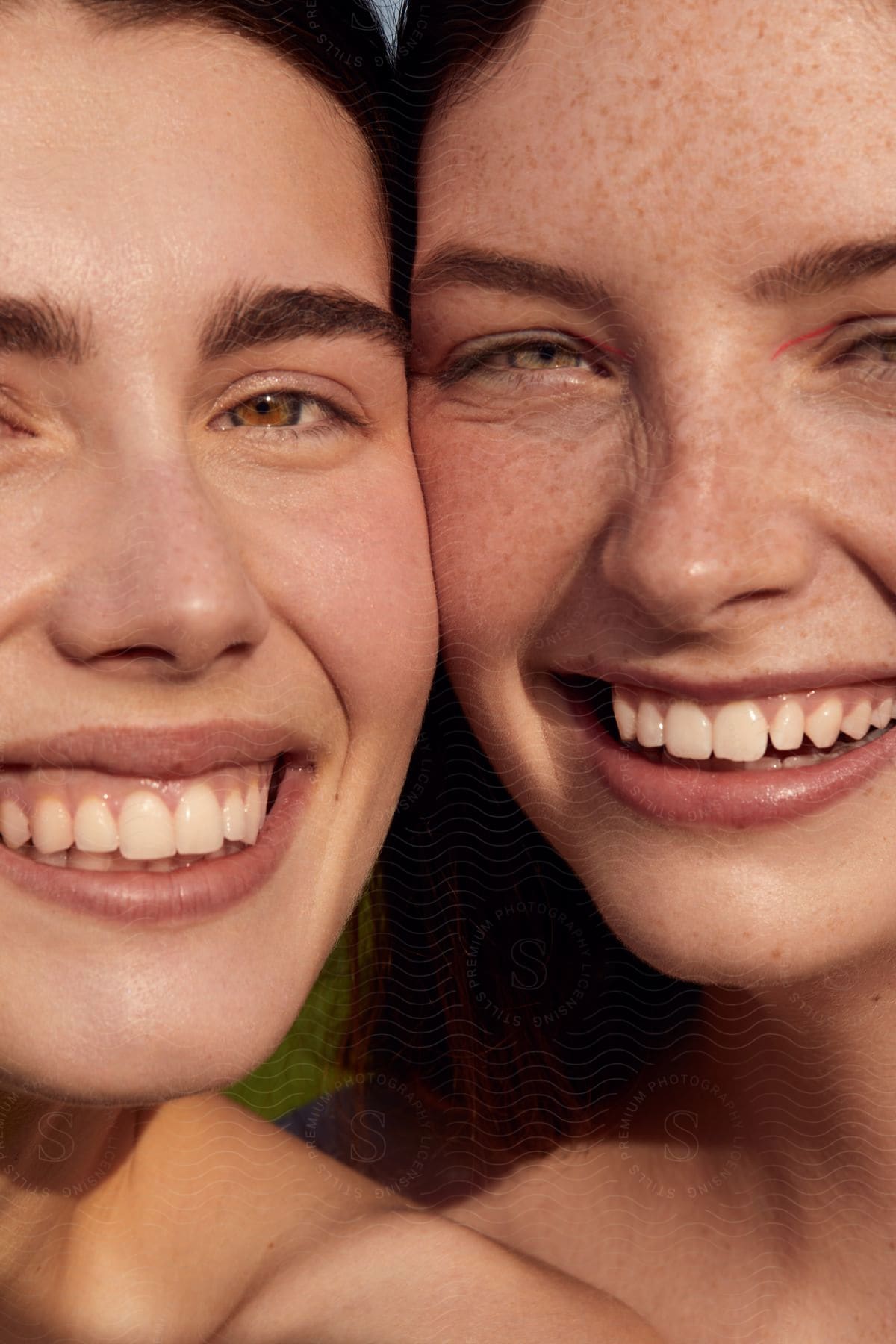 The face of two young women who are smiling and their faces have natural lighting.