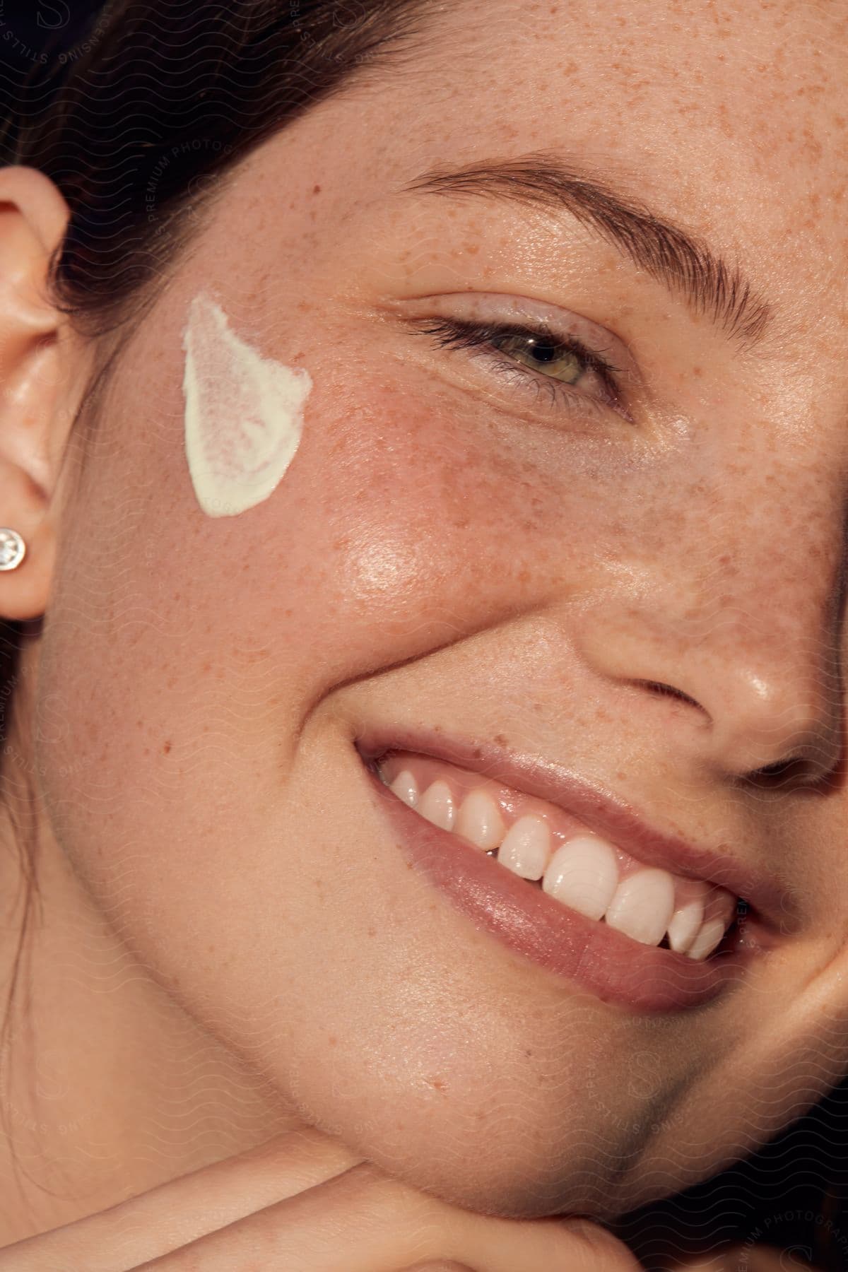 A young smiling woman with facial cream on her face.