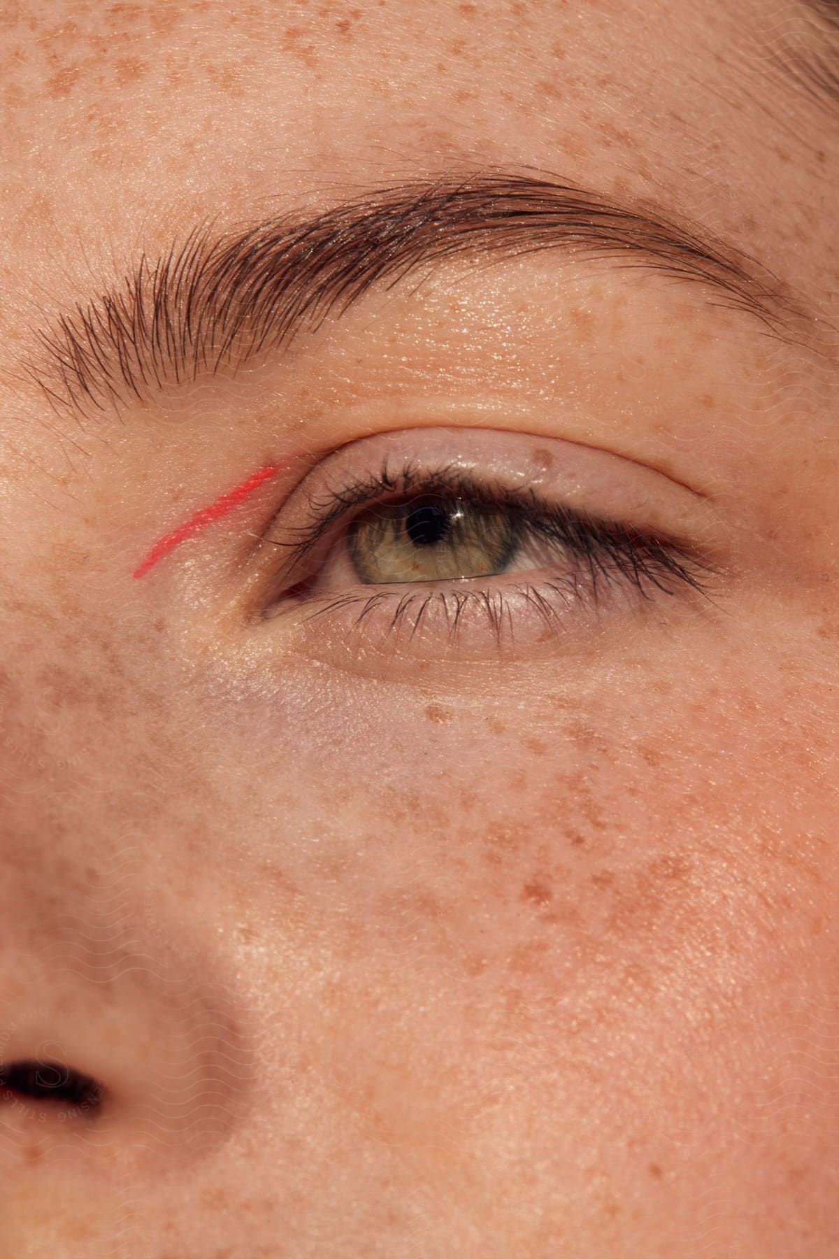 Close up of a woman's left eye, wearing make-up, a small red line by the bridge of her nose.