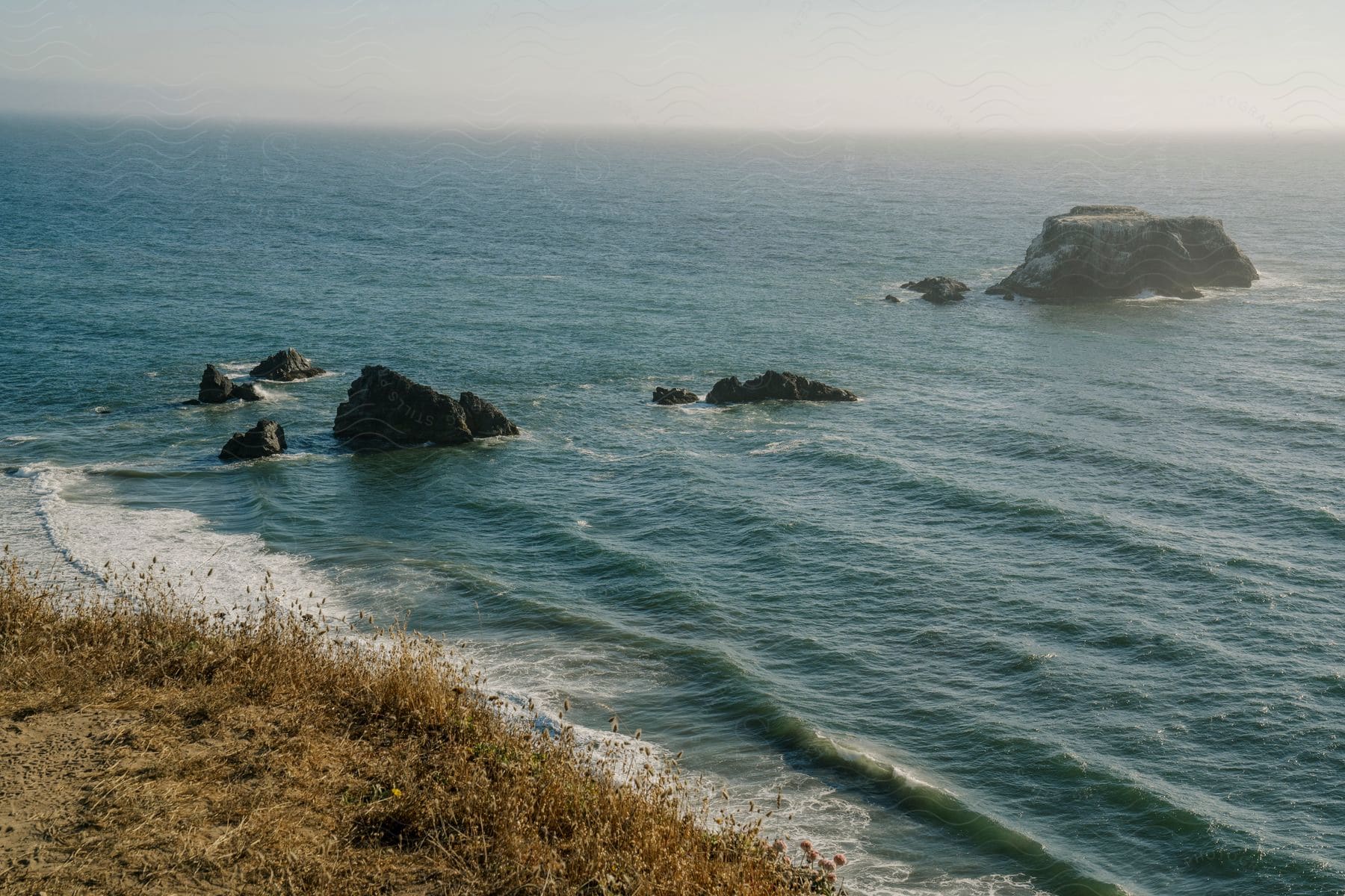 a group of rocks in the middle of the ocean, with waves crashing against them.