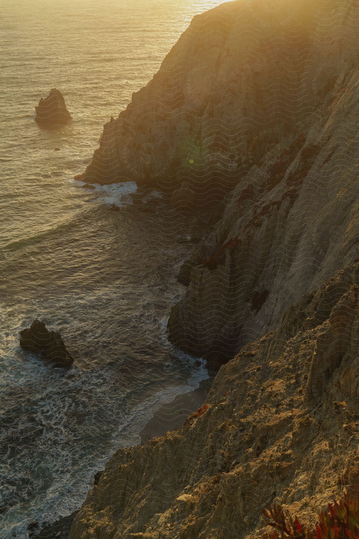 Setting sun glares across rocky seaside cliffs.
