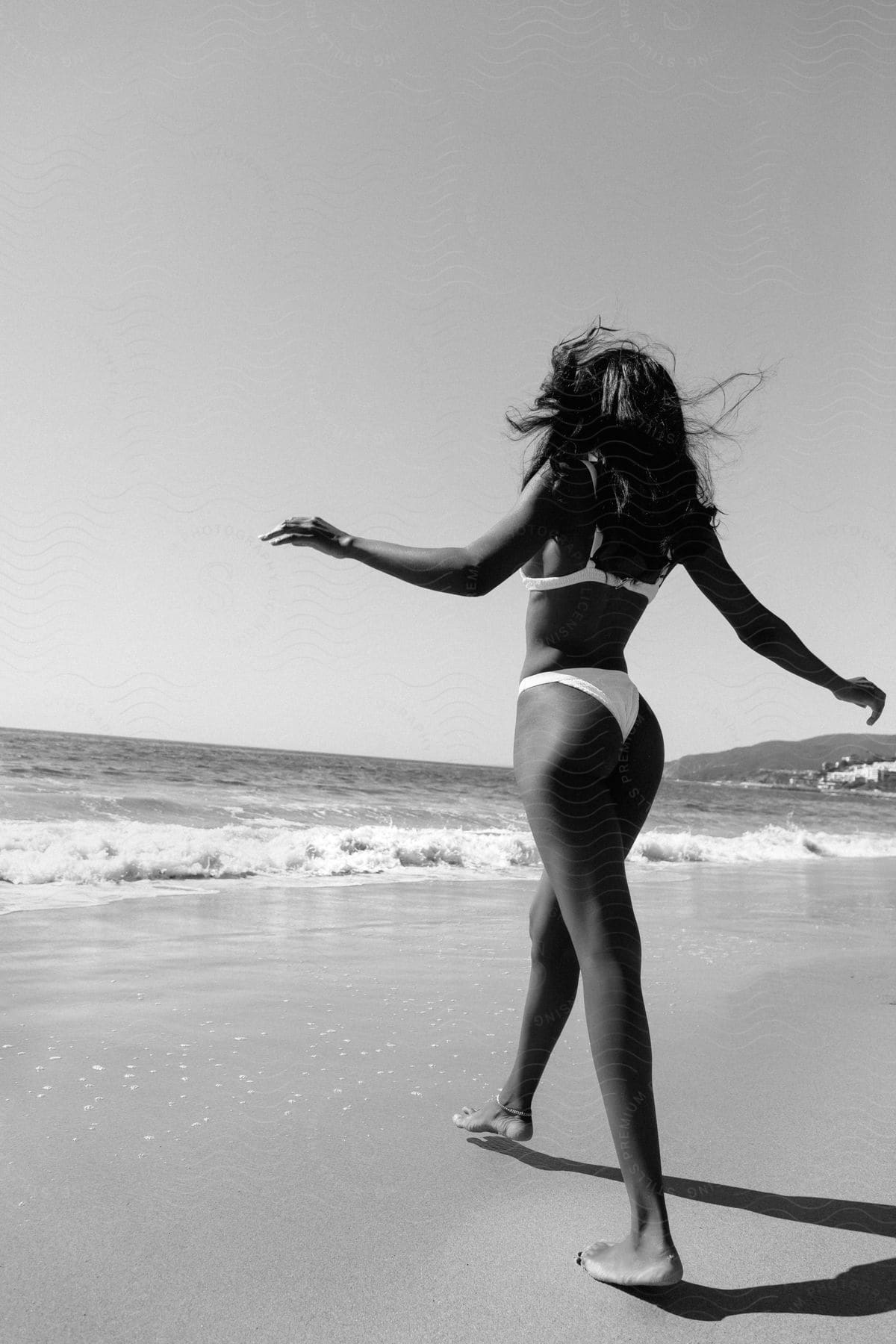 A woman walking in a bikini down the beach on a sunny day.