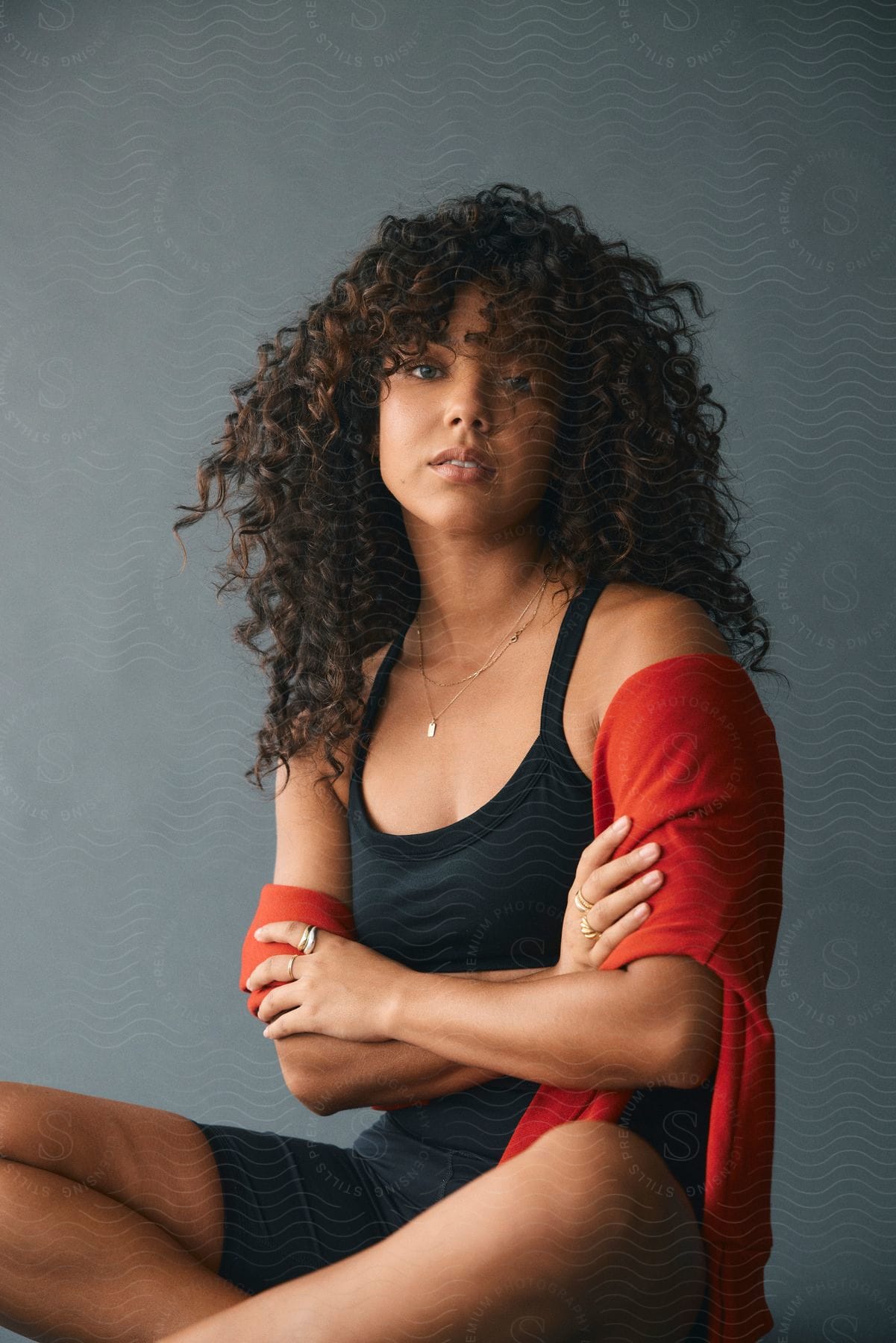 A young woman is sitting on the floor with her legs crossed and arms folded