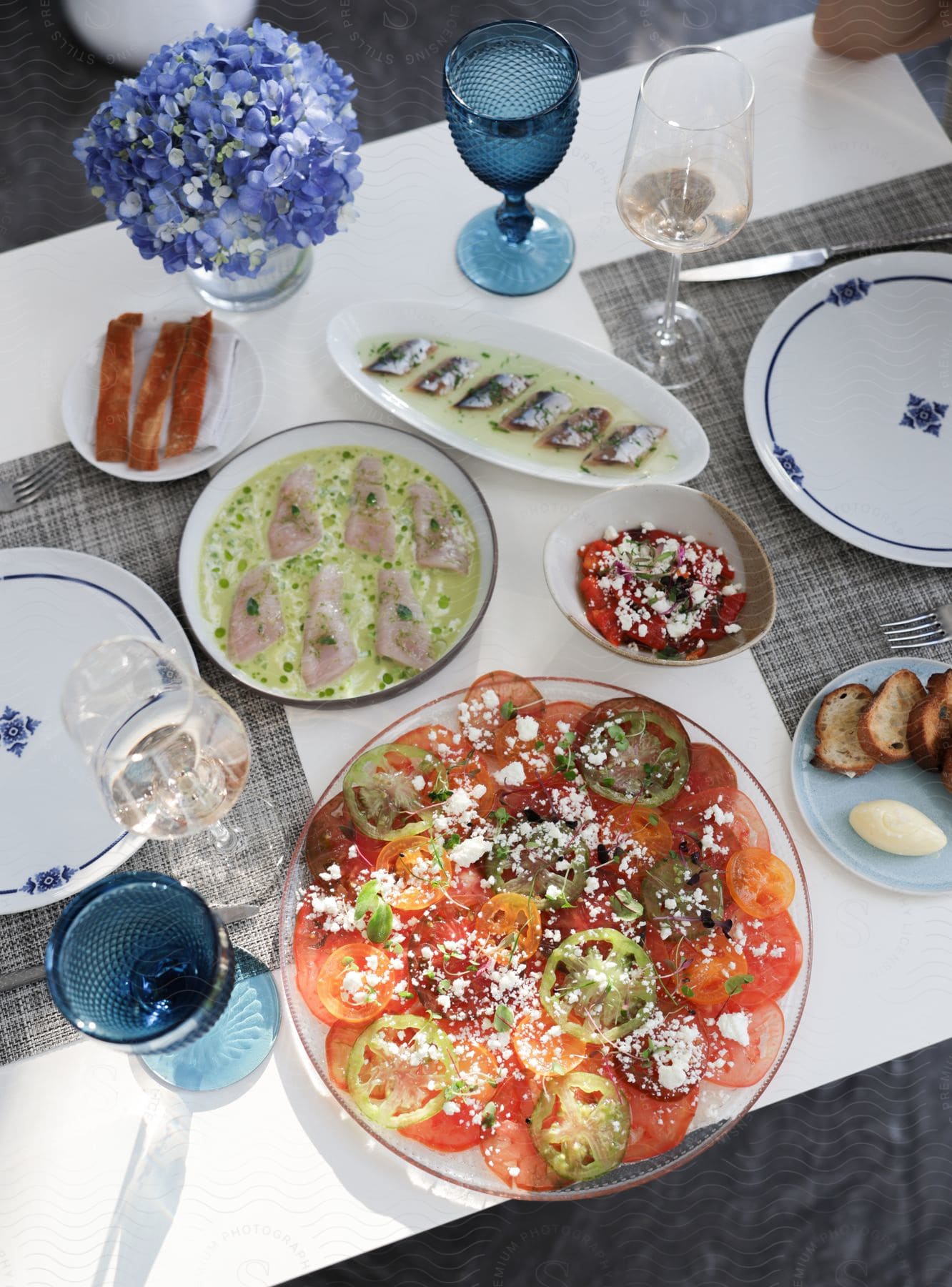 A meal containing fresh fish and sliced tomatoes is placed on a dinner table.