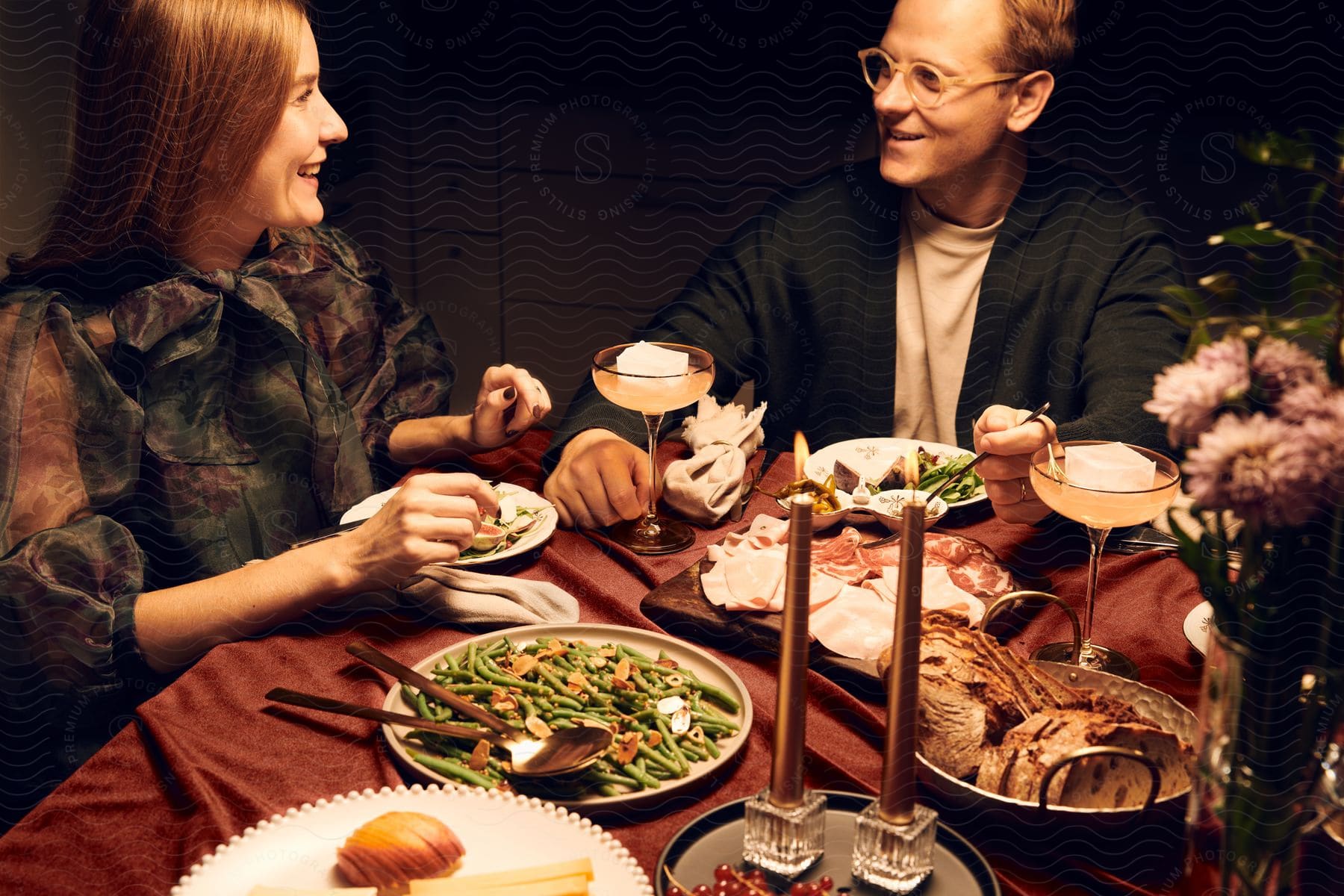 Man and woman sit at dinner table smiling at each other.