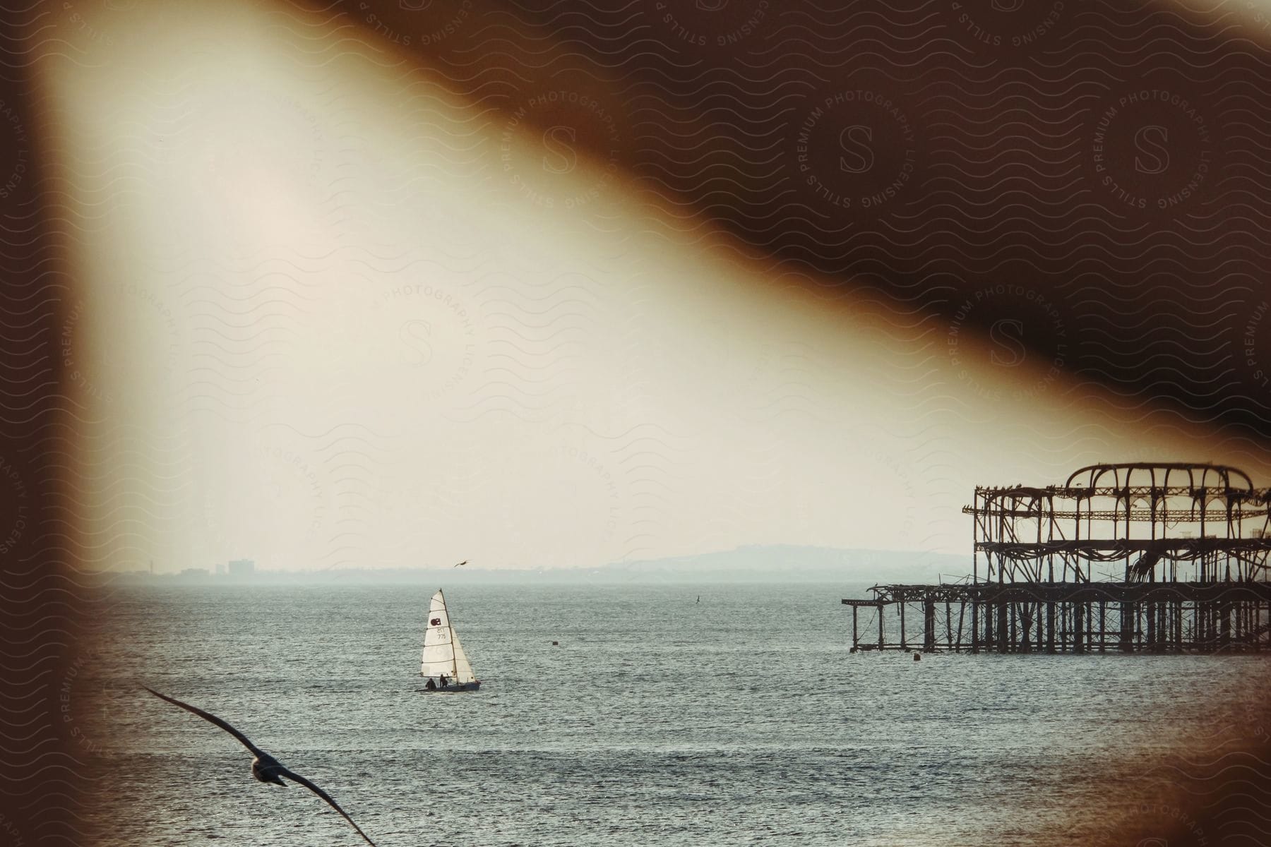 a sailboat floating on top of a body of water with a pier in the background