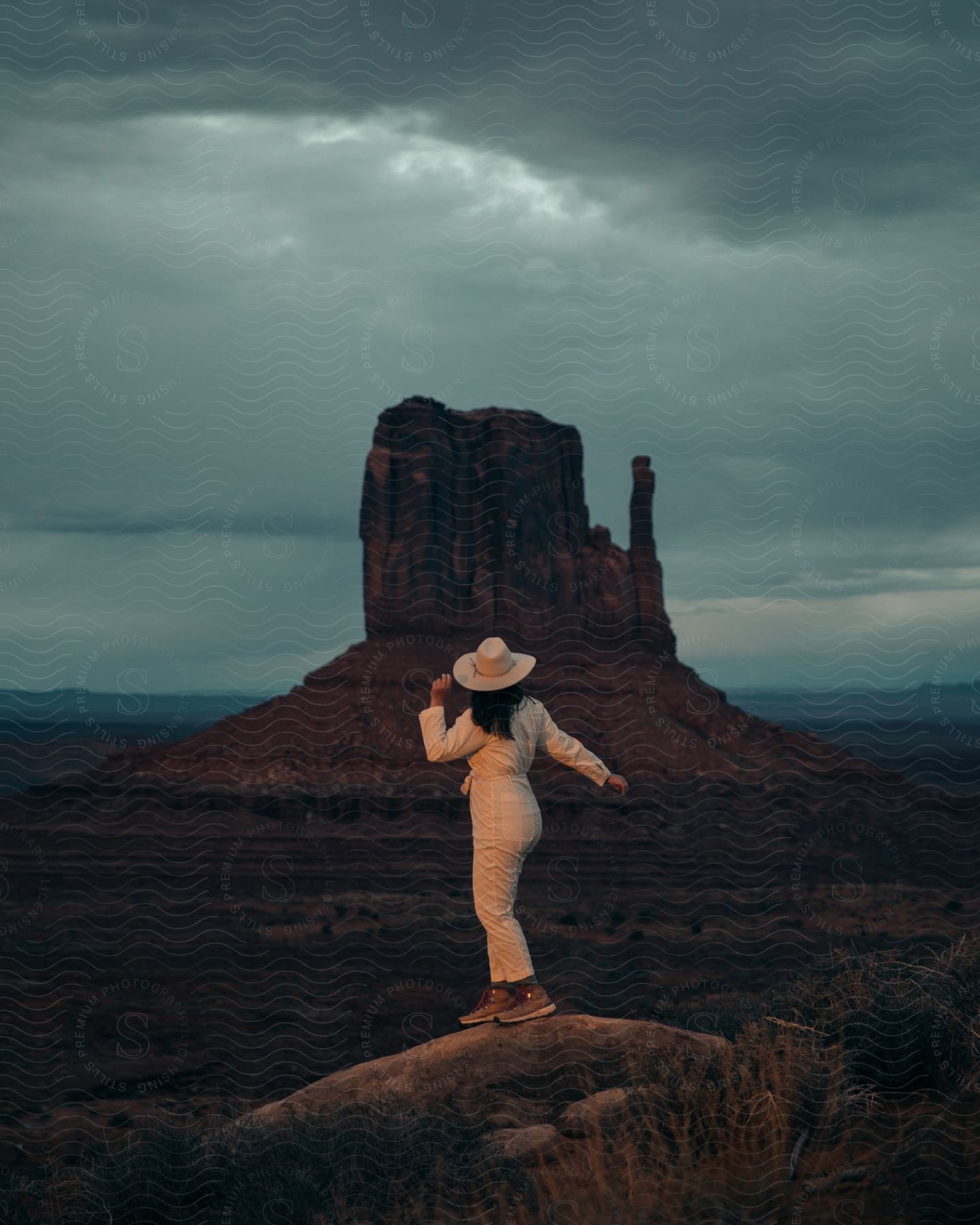 A woman wearing a hat looks at one of the famous rocks in Monument Valley.