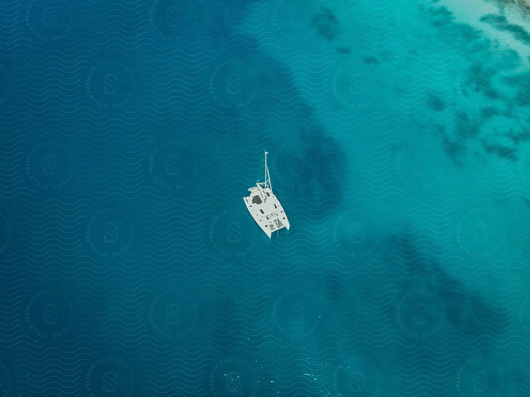 Aerial view of a white boat floating near an ocean beach.