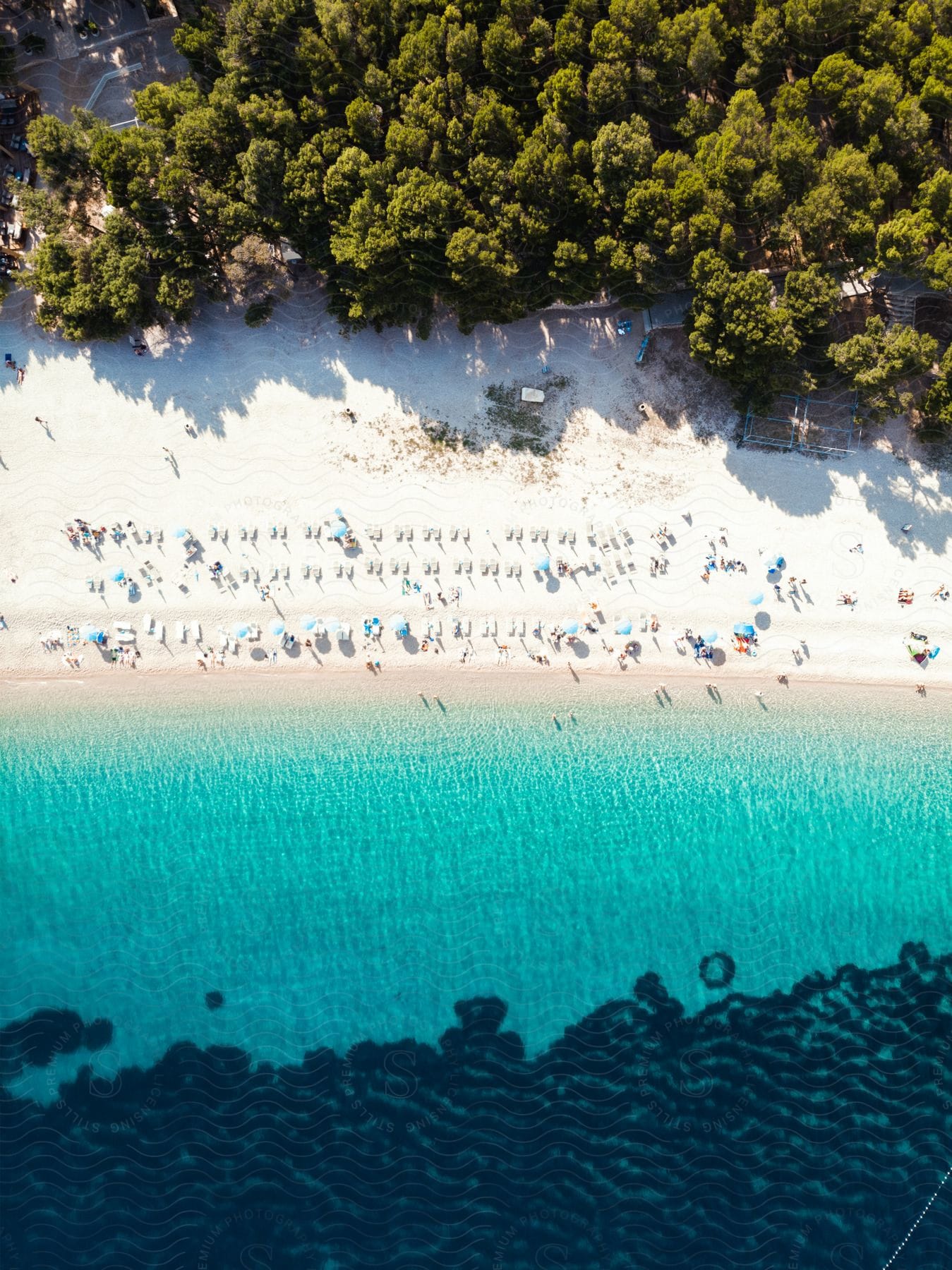 An aerial view of people on white sand beach with clear turquoise ocean