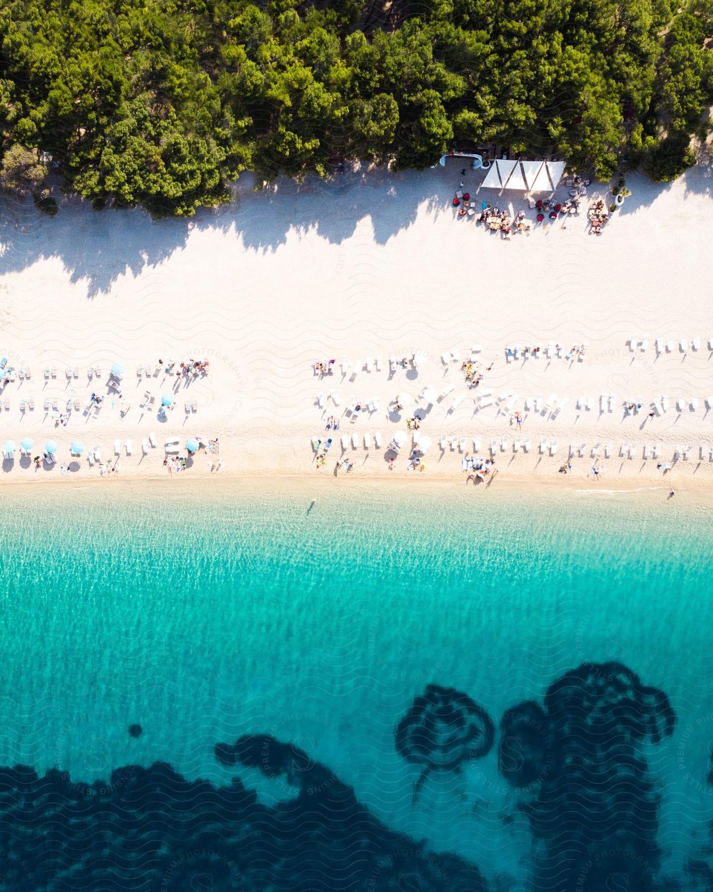 An aerial view of people laying out on the beach at the edge of the ocean.