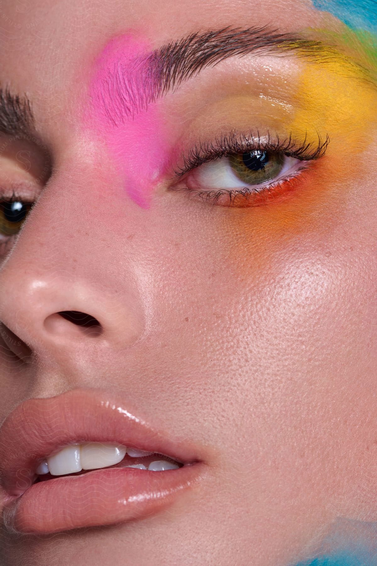 A woman with some colorful makeup on her face around her eye