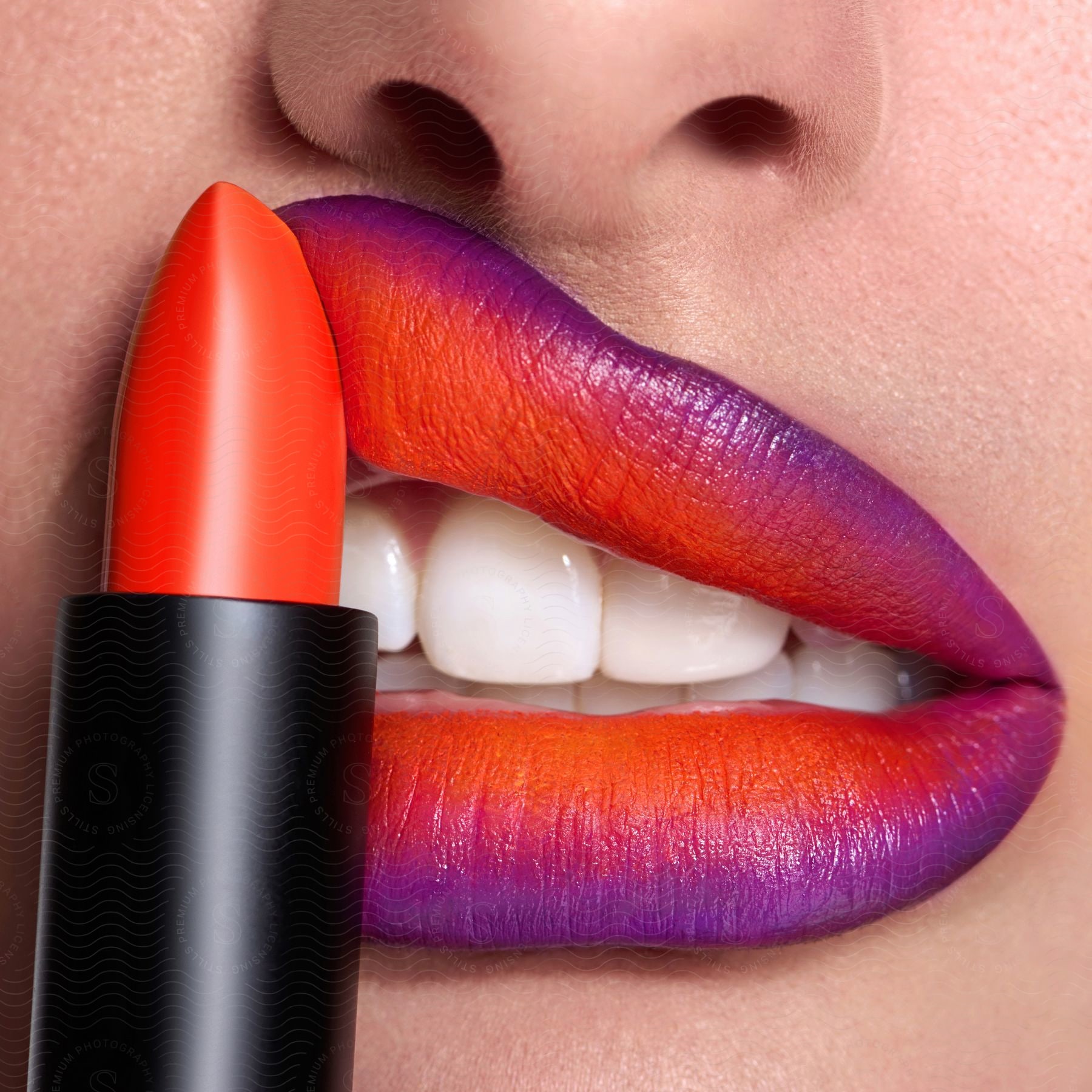 Stock photo of a woman putting red lipstick on her lips close up