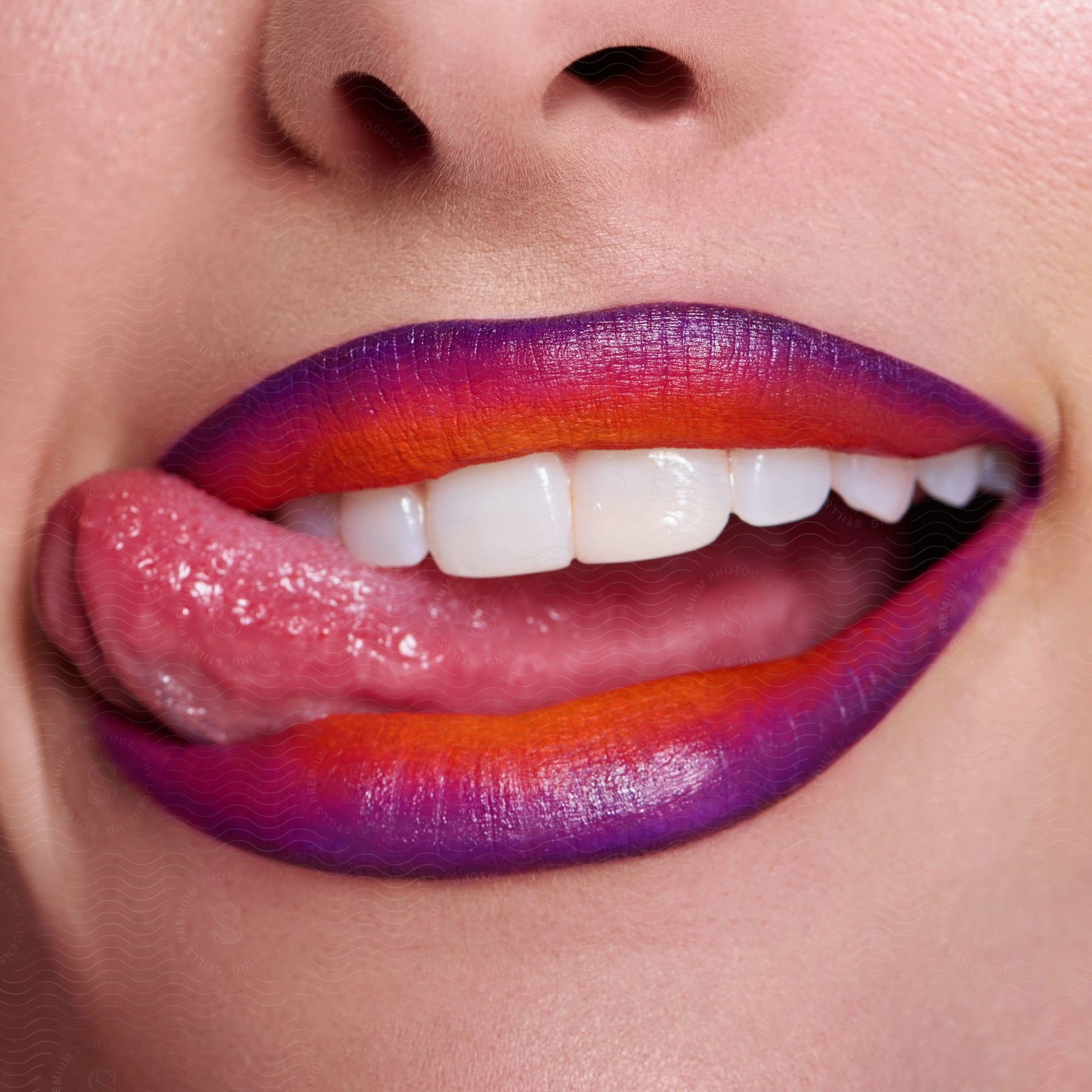 A woman's mouth wearing lipstick, with the tongue touching the corner of the mouth and the upper lip