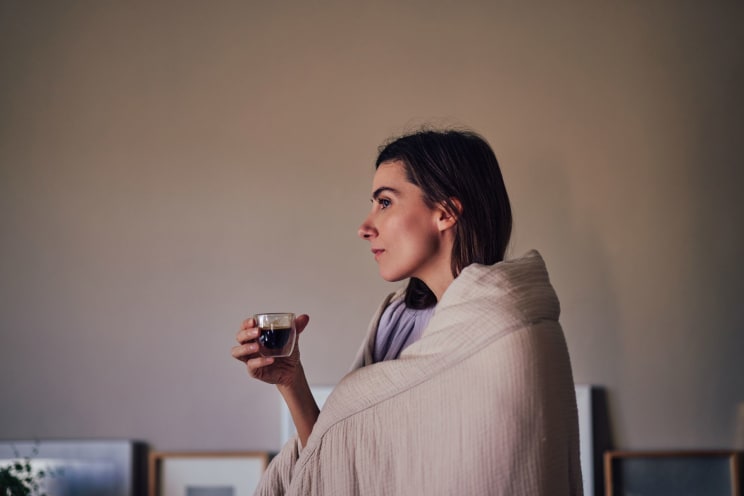 A Woman Wrapped In A Blanket Holding A Cup Of Coffee