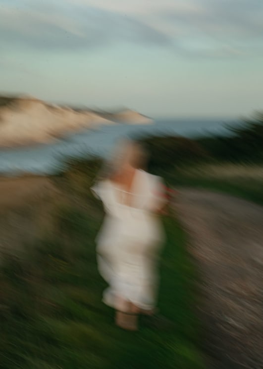 Blurry Shot Of A Woman Wearing A White Dress Near The Coast