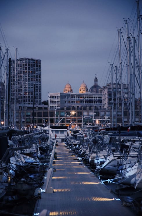 Boats Are Docked In The Marina With City Buildings In The Distance