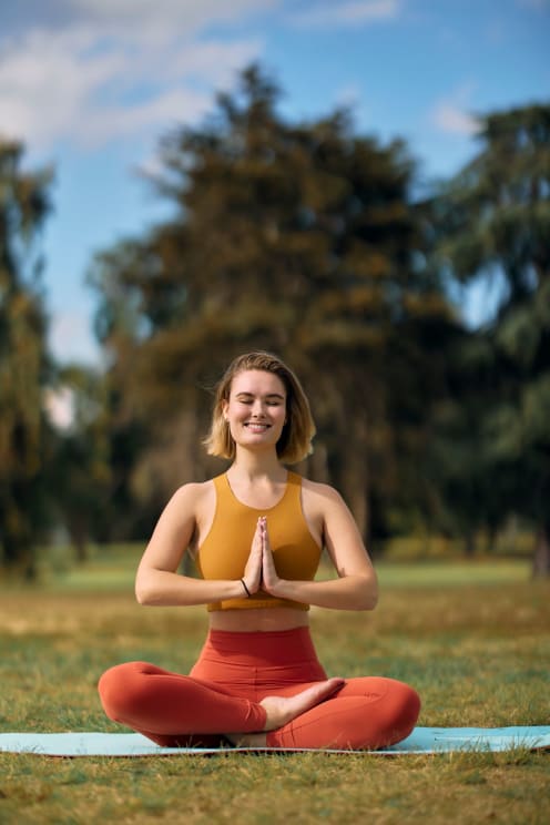 A Young Lady Doing Yoga In A Grassland